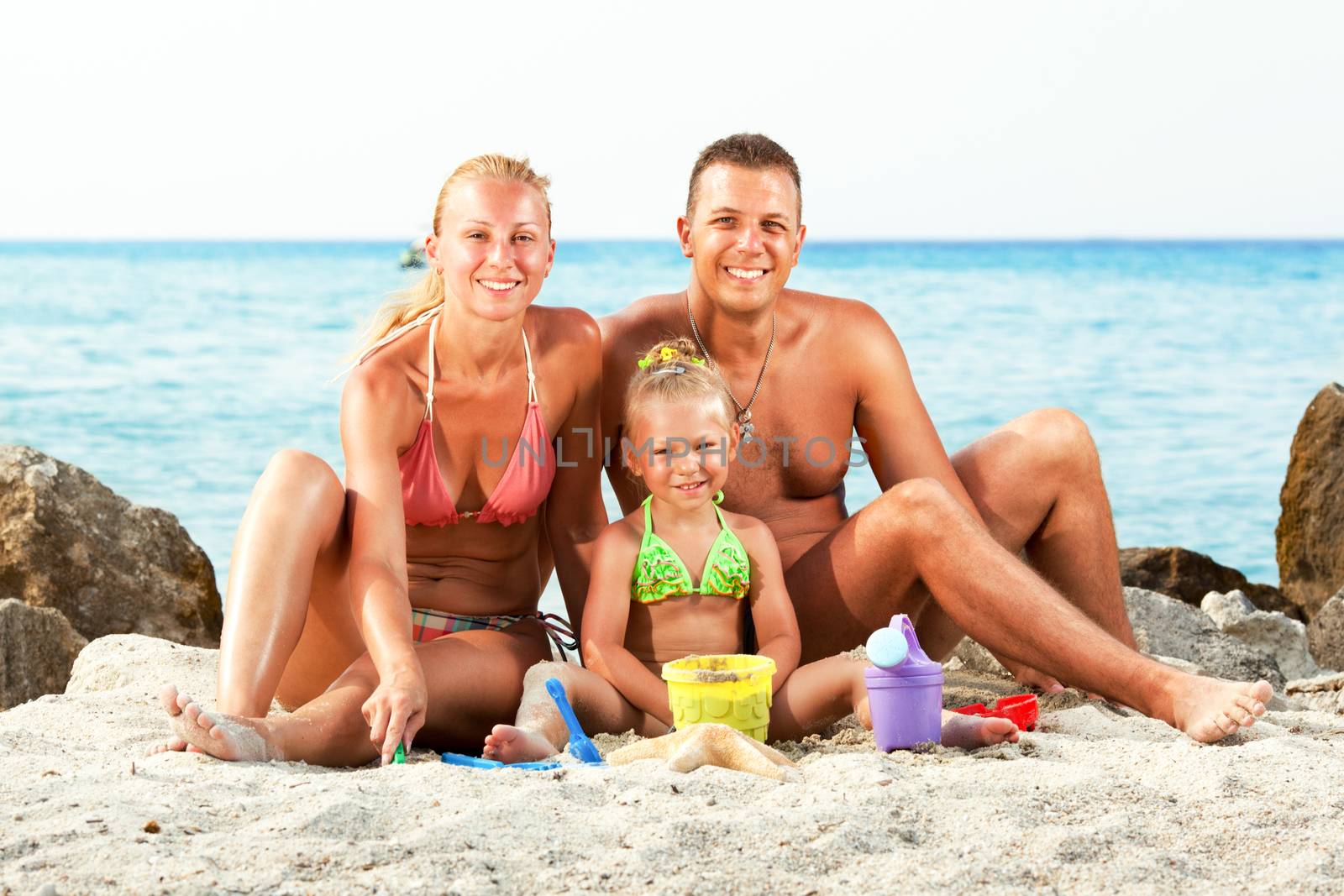 Happy family on the beach with bucket and spade