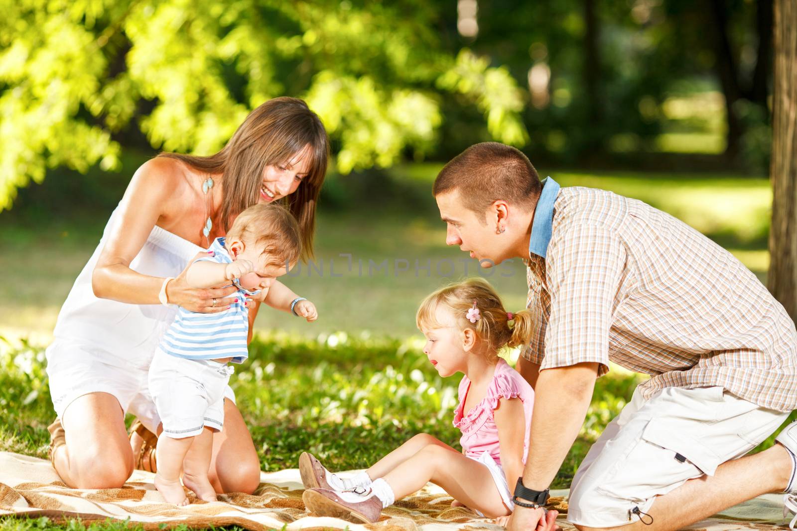 Baby boy makes first steps with his family in beautiful nature