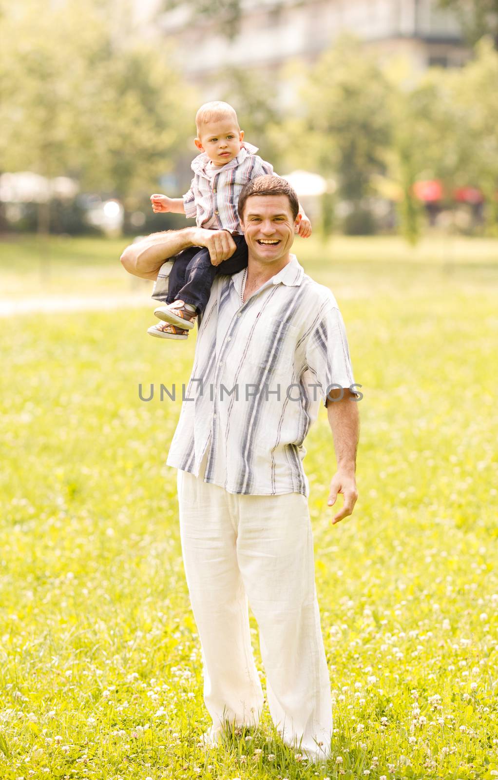 Father holding his son on shoulder and walking through park