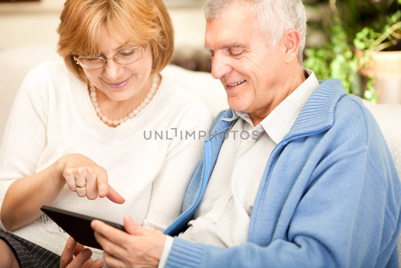 Happy senior couple using tablet at home