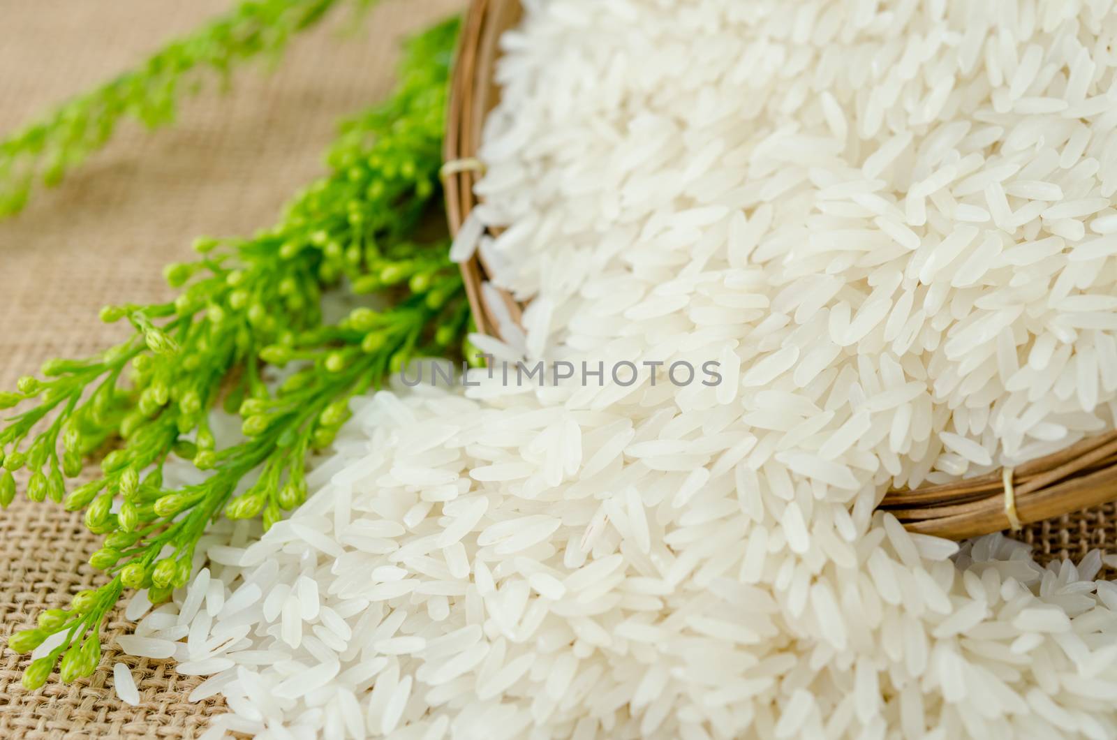 Jasmine rice in weave wooden basket with flower. by Gamjai