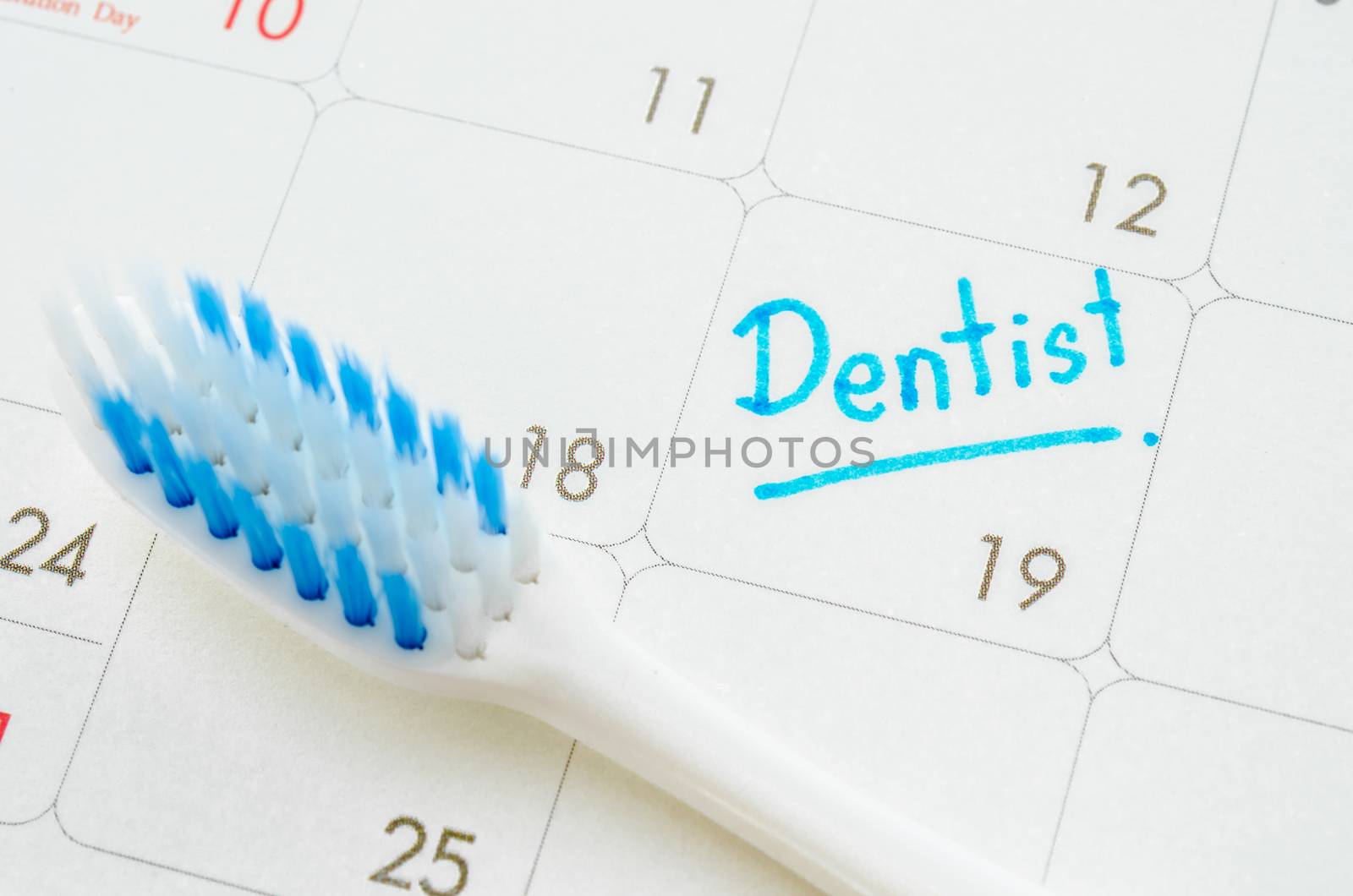 The words Dentist written on a calendar to remind you an important appointment with tooth brush.