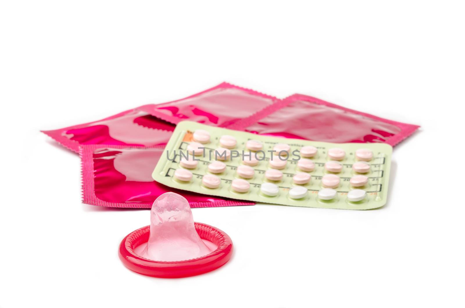 Strip of Contraceptive Pill and condoms on whie background.