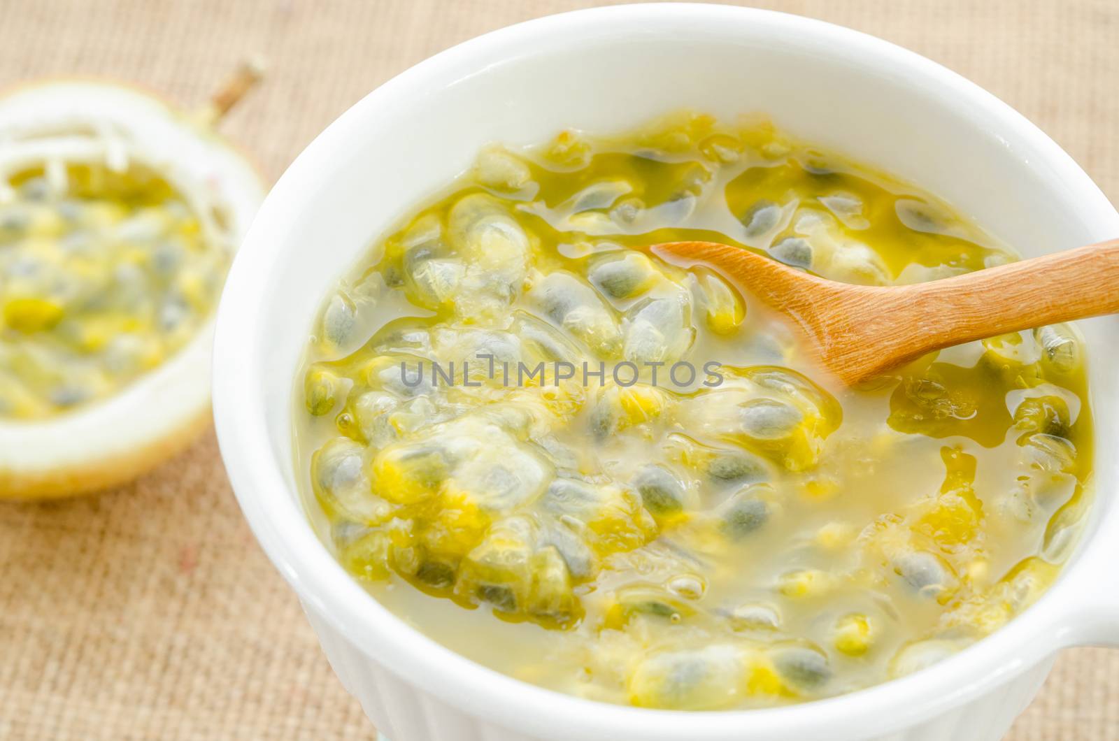 Passion fruit juice white bowl with wooden spoon on sack background.