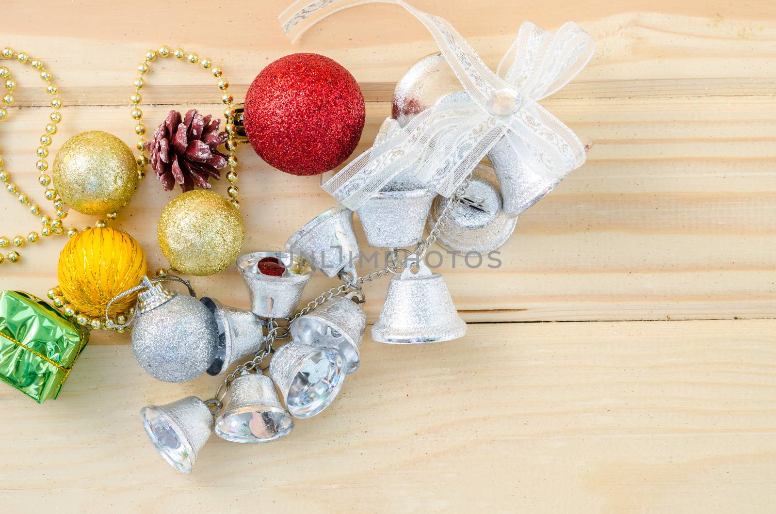 Silver bell with colorful christmas decorations on wooden background.