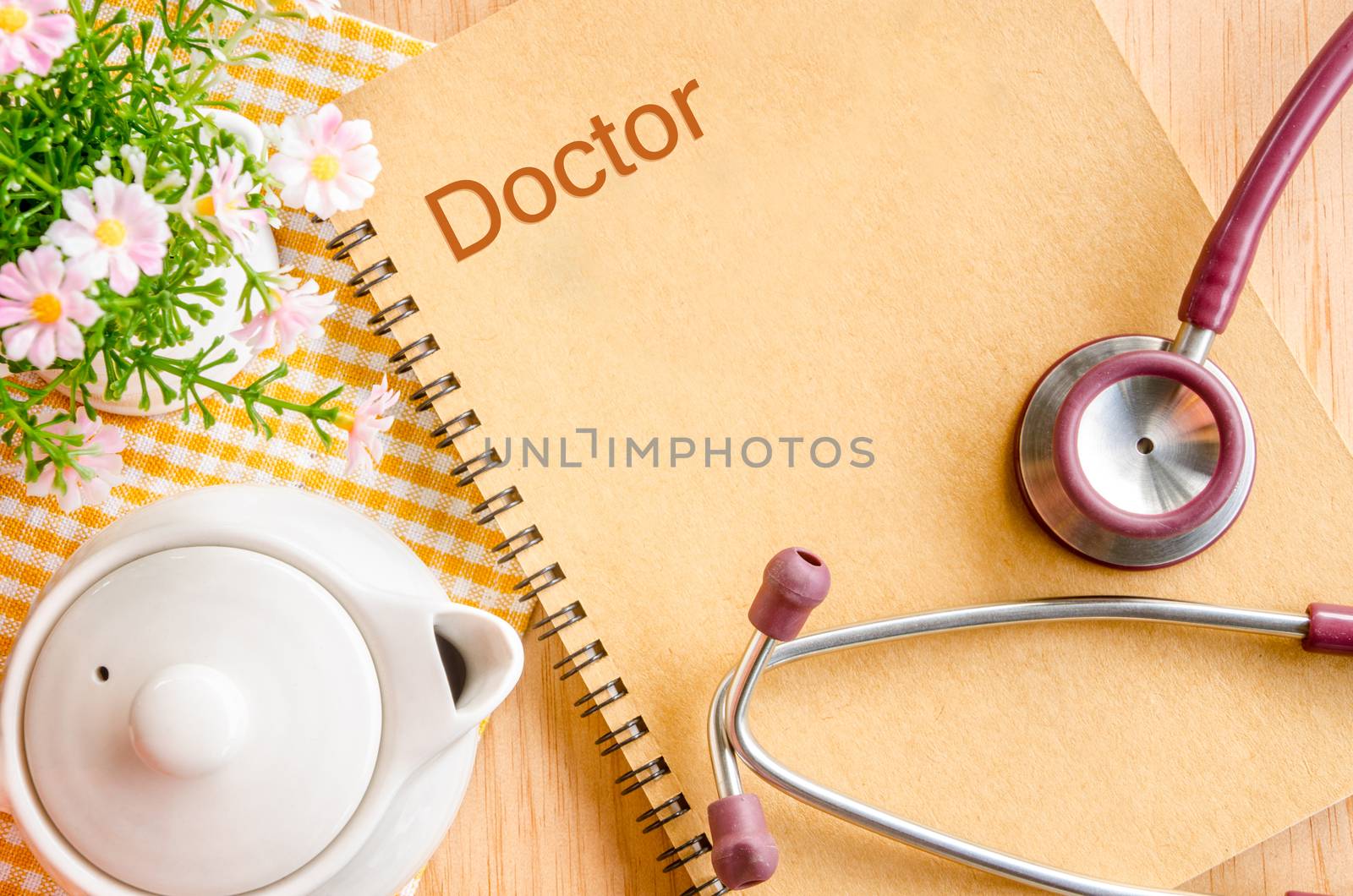 Stethoscope With Note Book with flower on wood background.