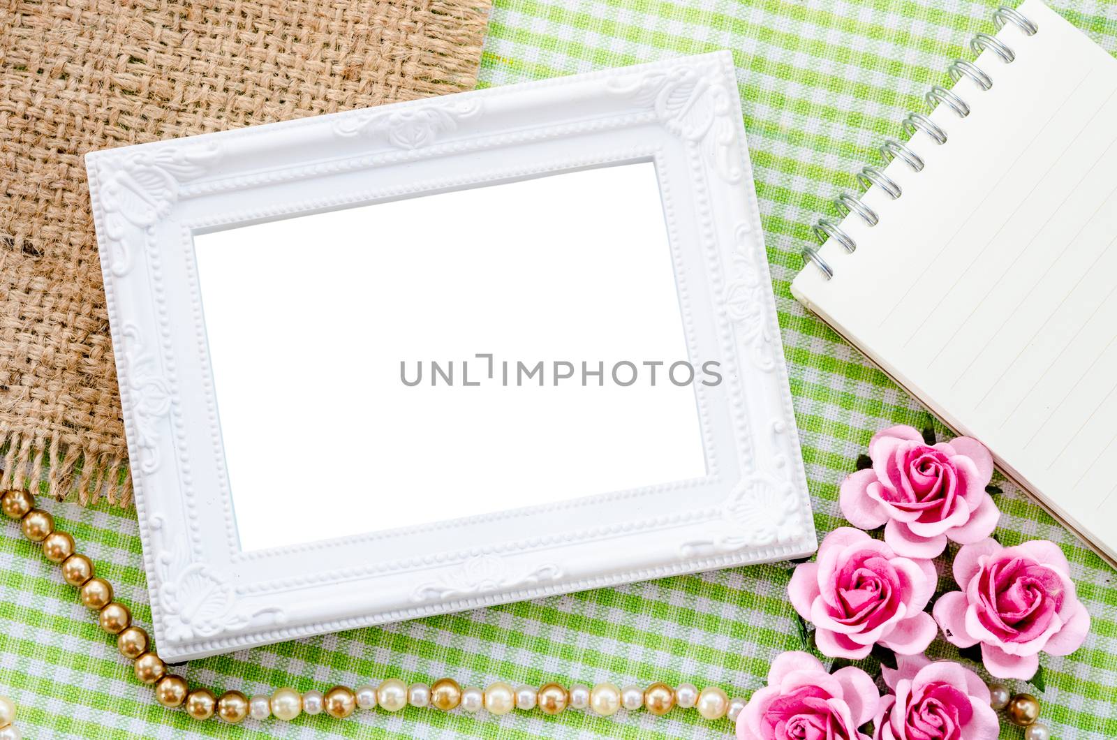 Blank vintage white photo frame and open diary with pink rose on fabric background. Save clipping path.