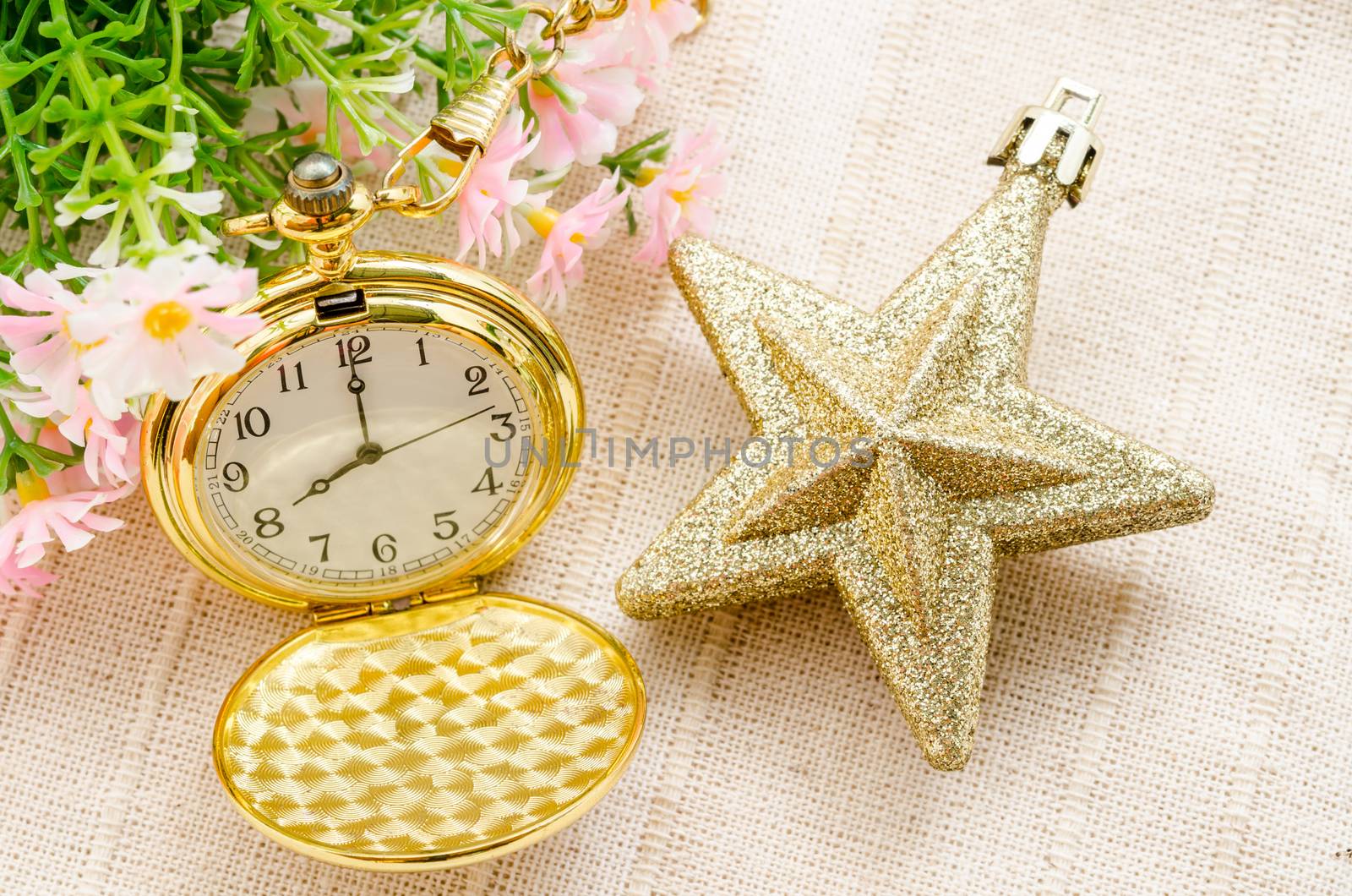 Gold pocket watch and gold star christmas with flower on fabric background.