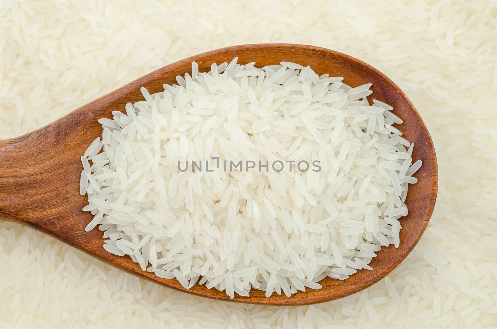 Raw white rice and wooden spoon.