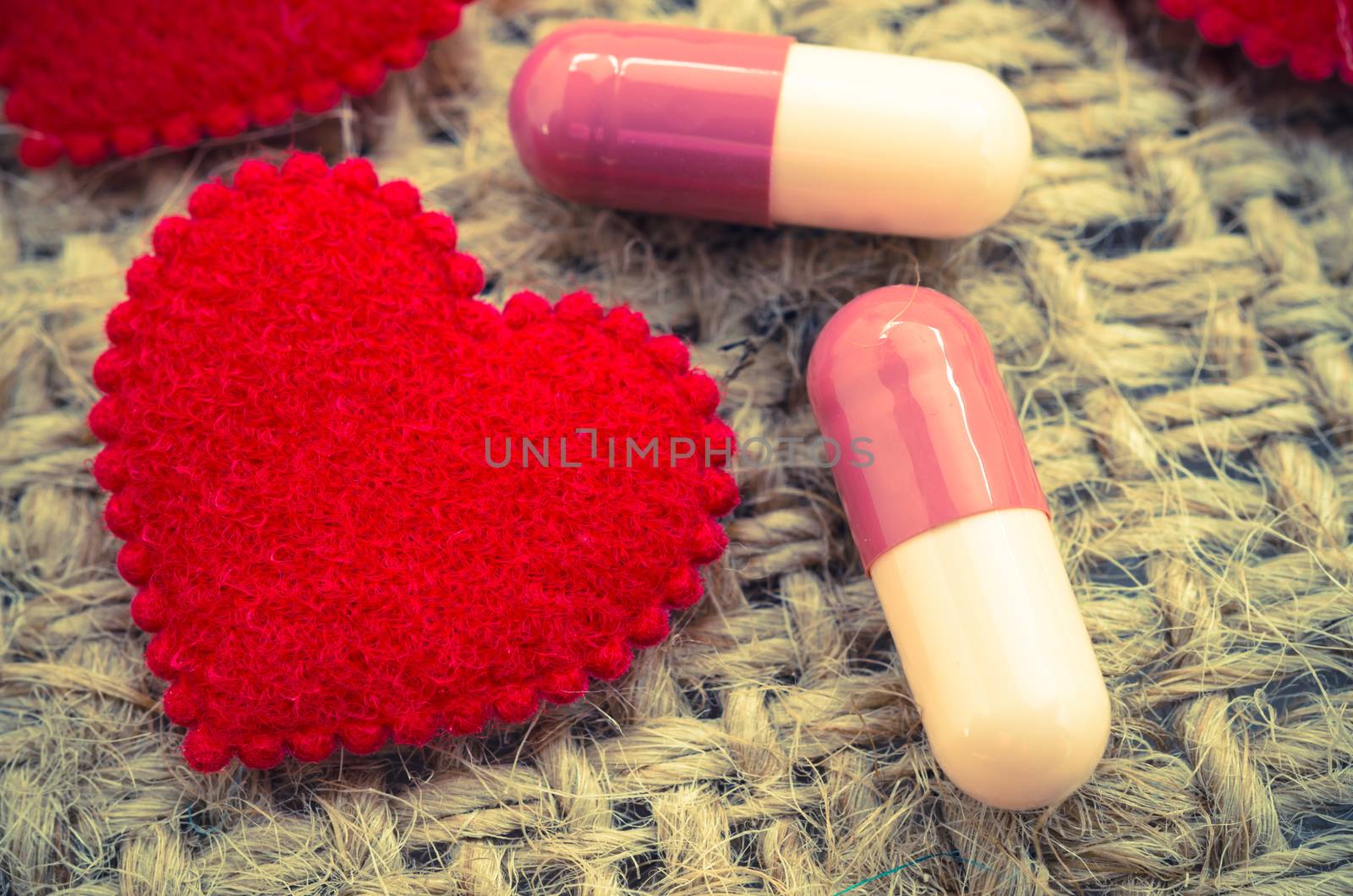 Capsule pill and red heart on sack background. by Gamjai