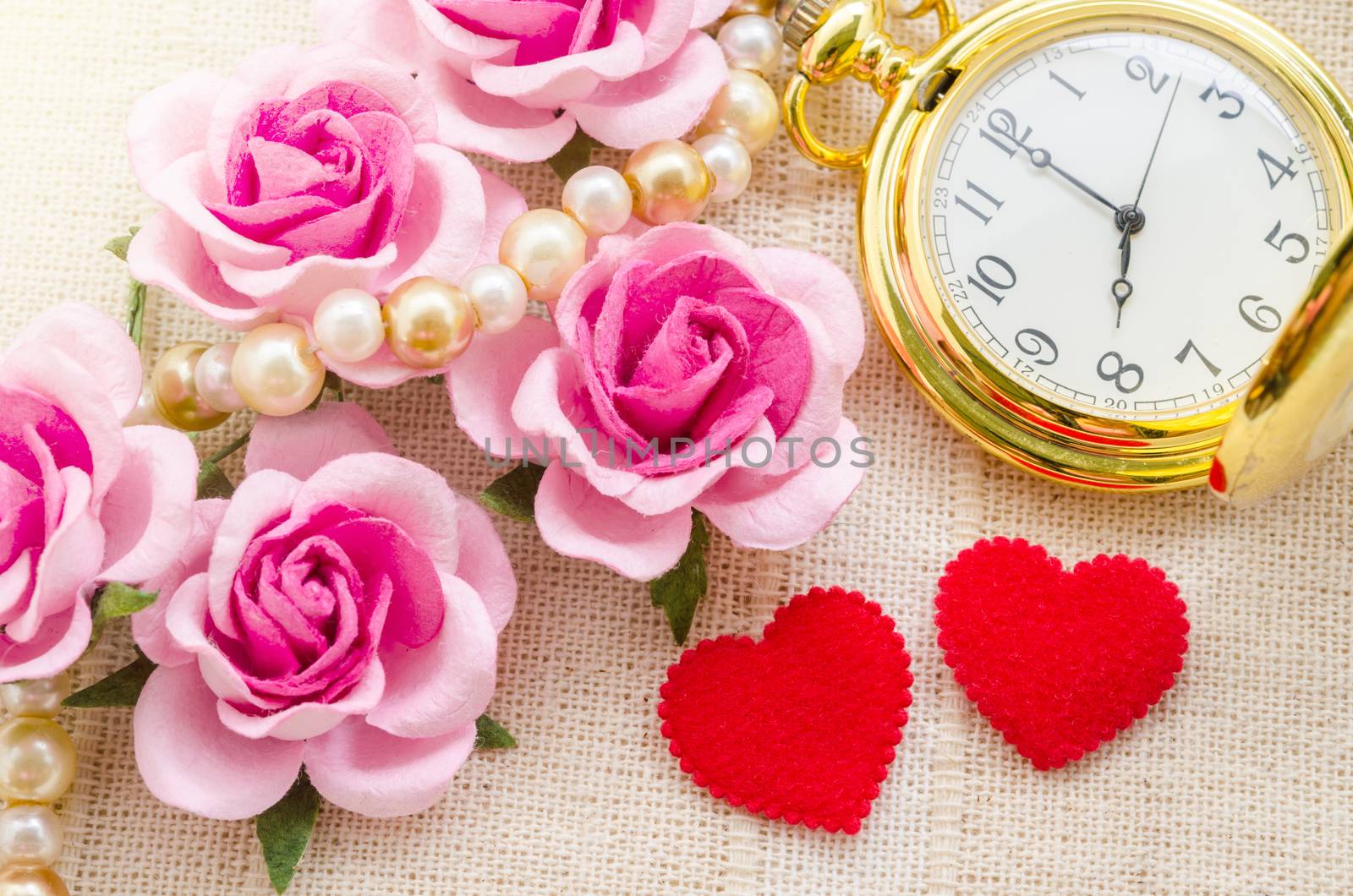 Red heart and pink rose with gold pocket watch on fabric background. Love of time concept.