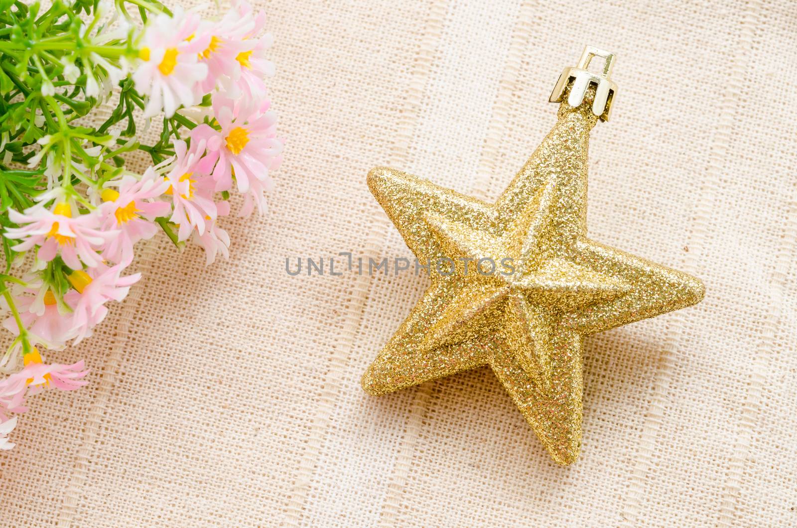 Gold five pointed star christmas decoration with flower on fabric background.