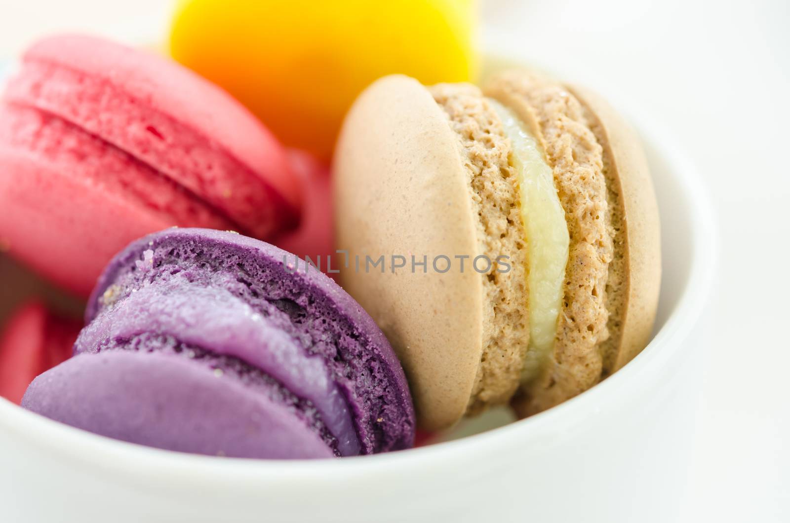 Colorful sweet macaroons in a ceramic cup isolated on a white background