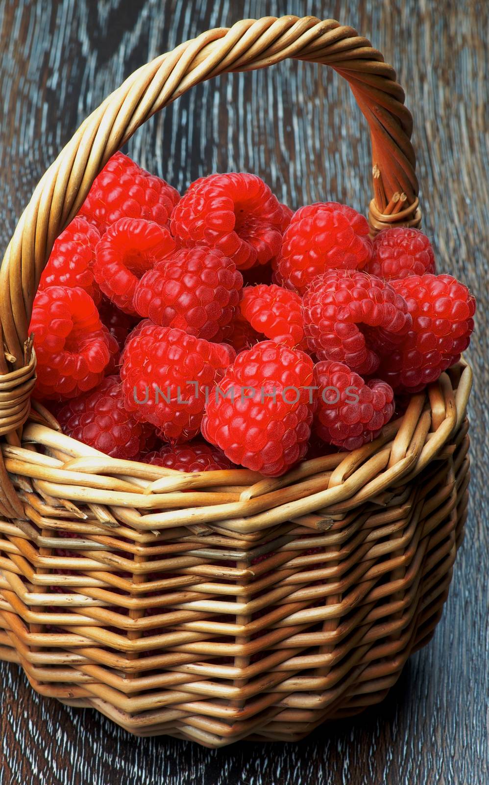 Fresh Ripe Raspberries Full of Wicker Basket Cross Section on Wooden background