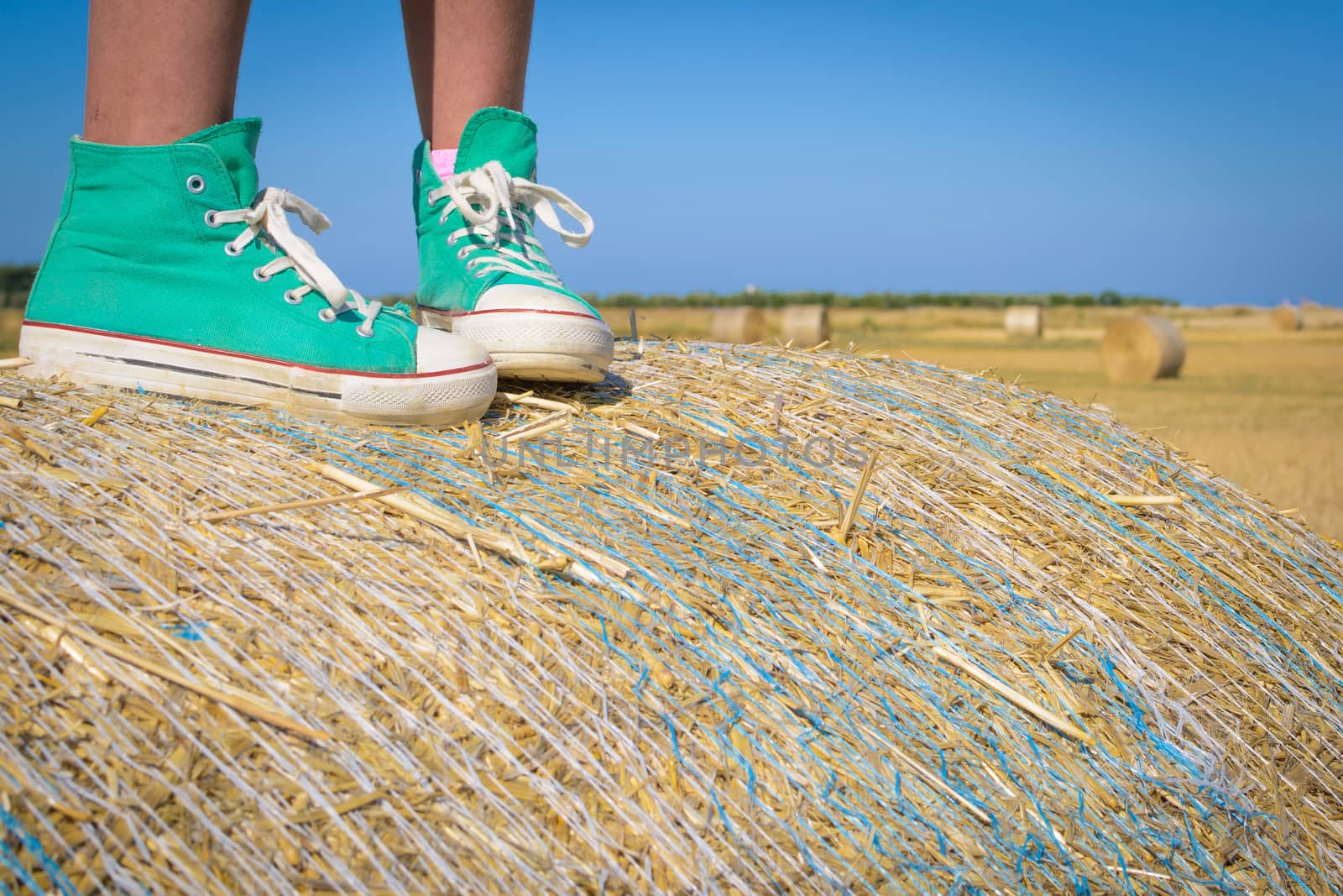 Feet of little girl on a hay bale