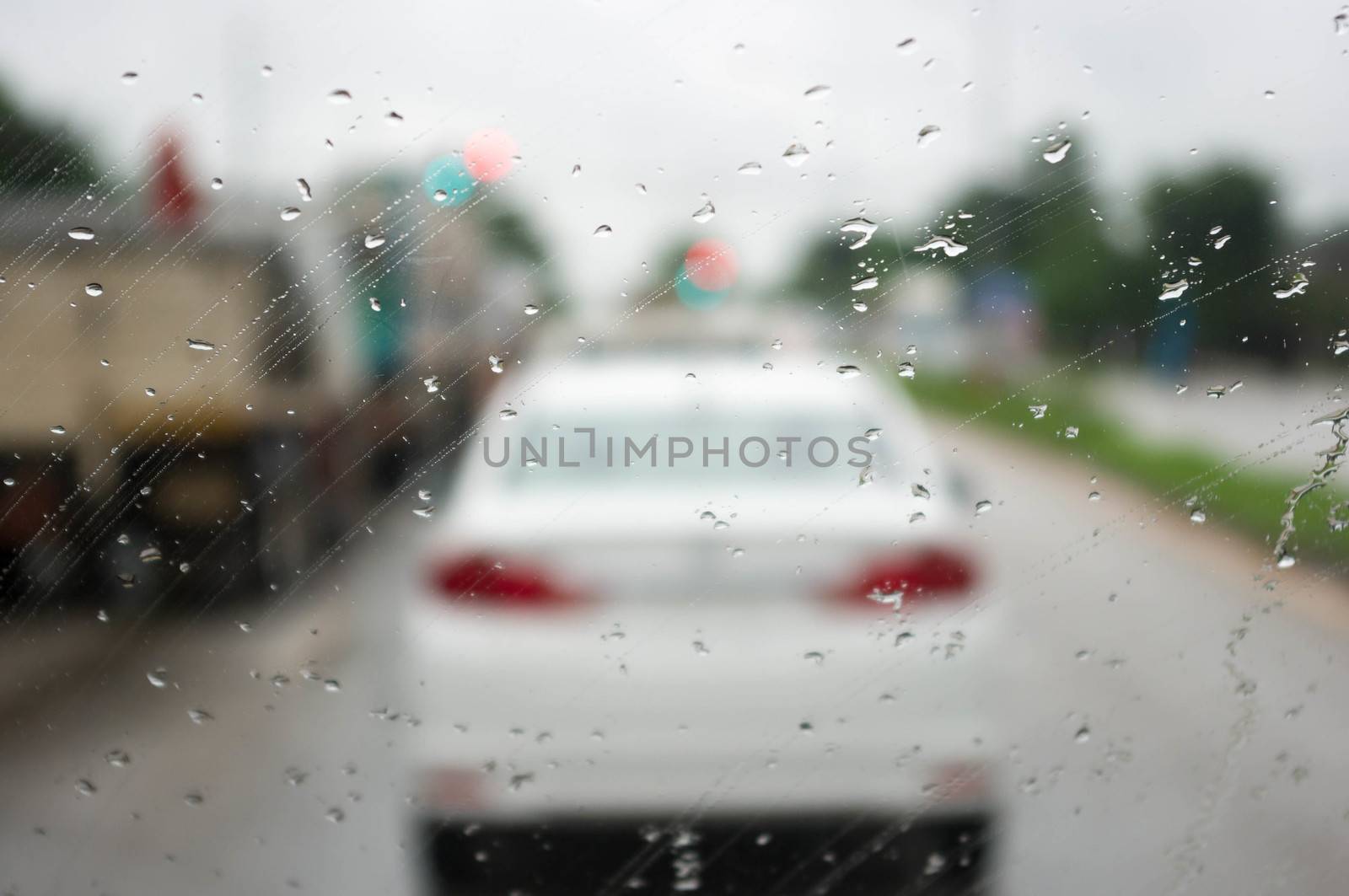 Road view through car window with rain drops