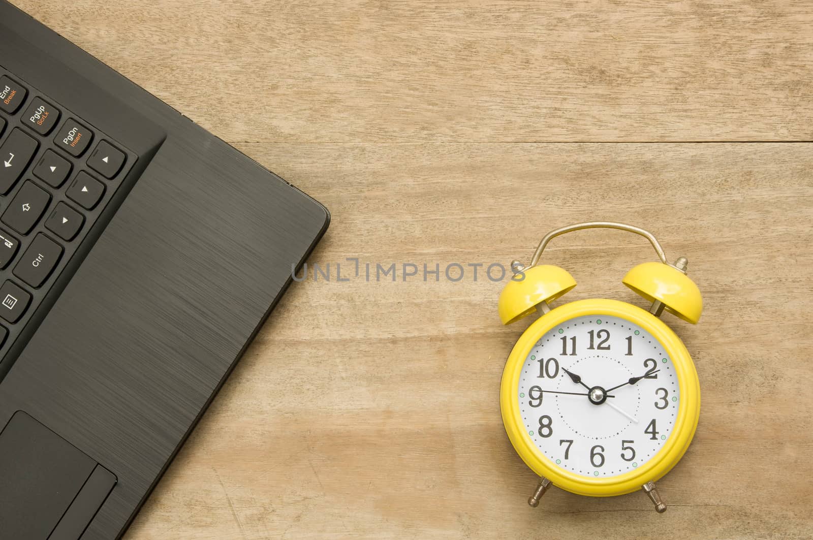 Black notebook  and yellow clock on woodenbackground.