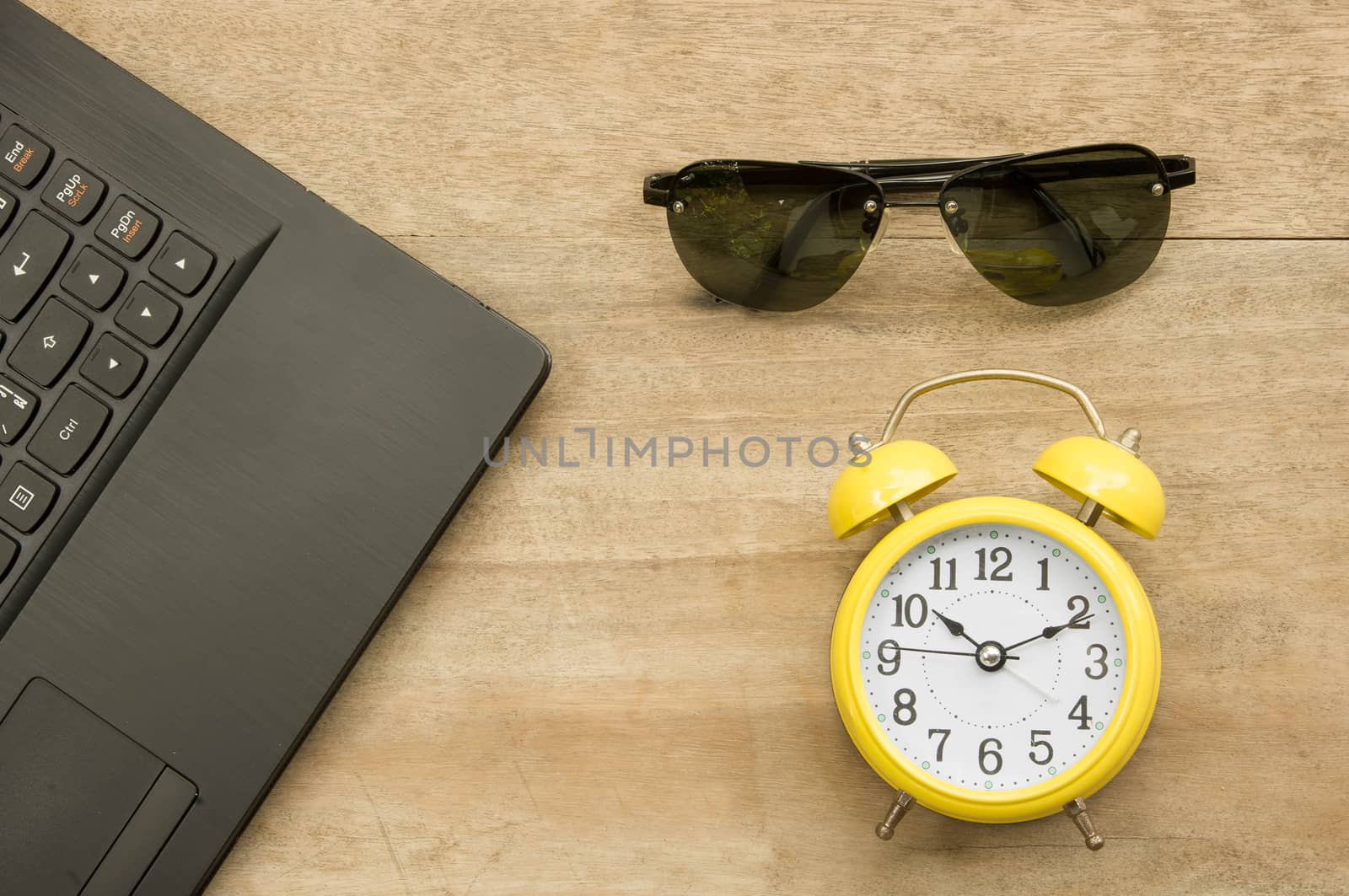 Black notebook  and yellow clock with eye glass on wooden by seksan44