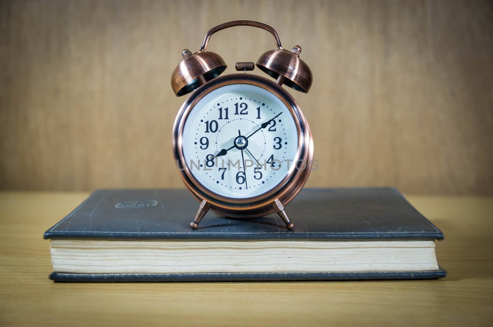 Vintage background with retro alarm clock and book on table