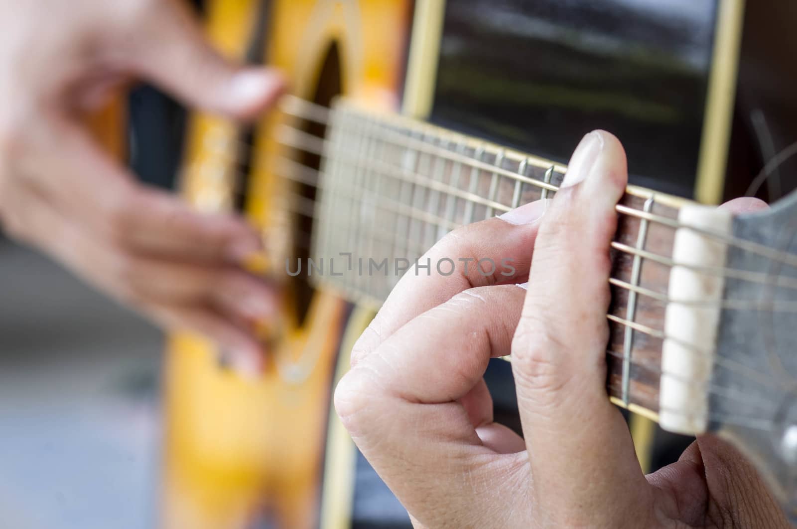 Hand playing acoustic guitar, by seksan44