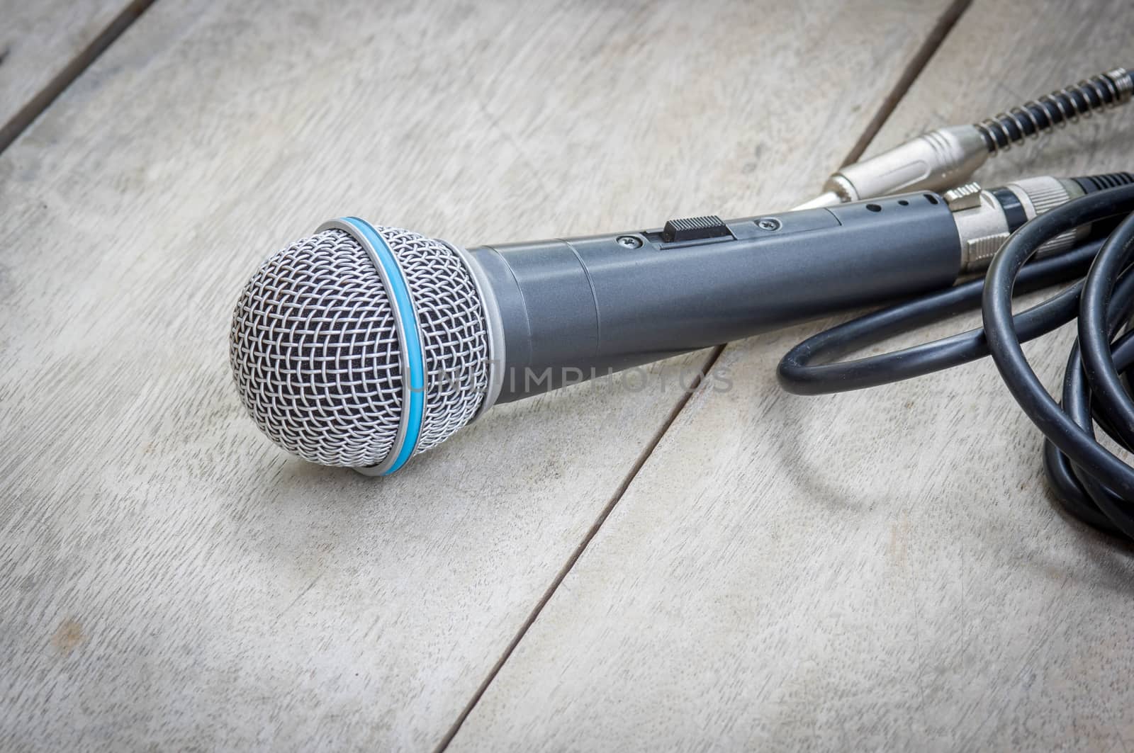 Black microphone on wood texture background.