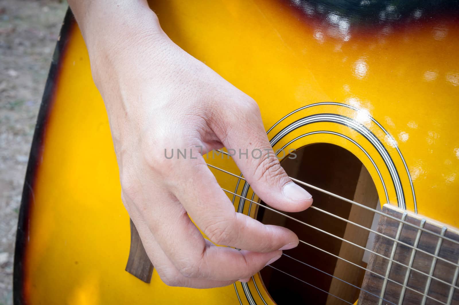 Hand playing acoustic guitar, close up