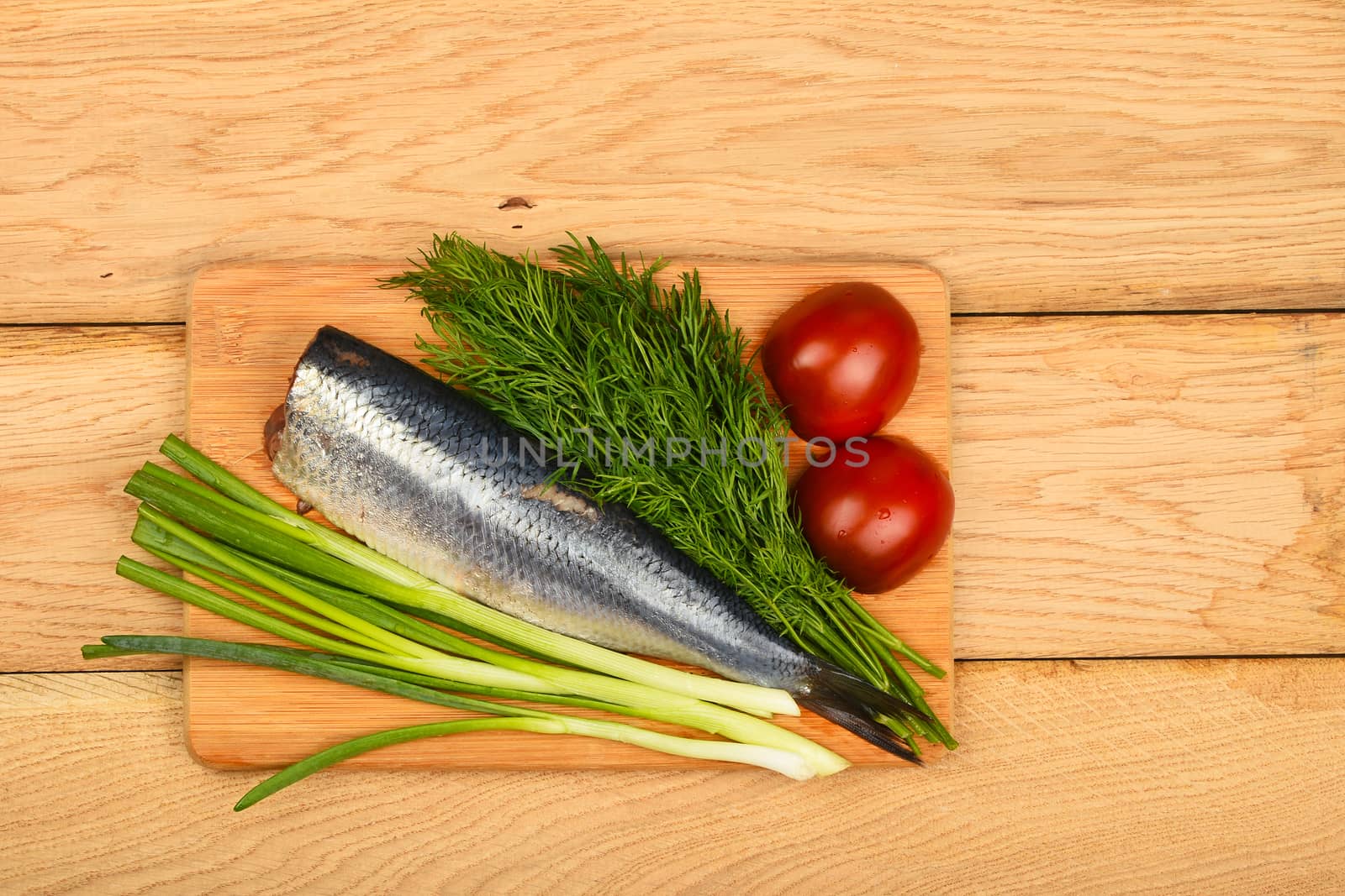 Herring double fillet with onion, dill and tomatoes on bamboo board on vintage wooden table surface