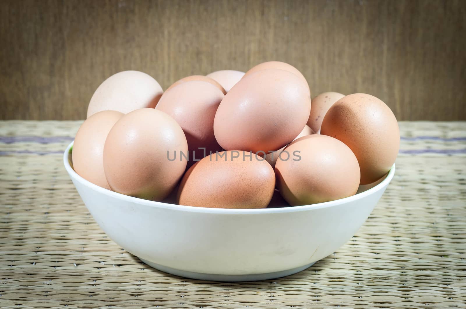 Chicken eggs in a dish on wood background.
