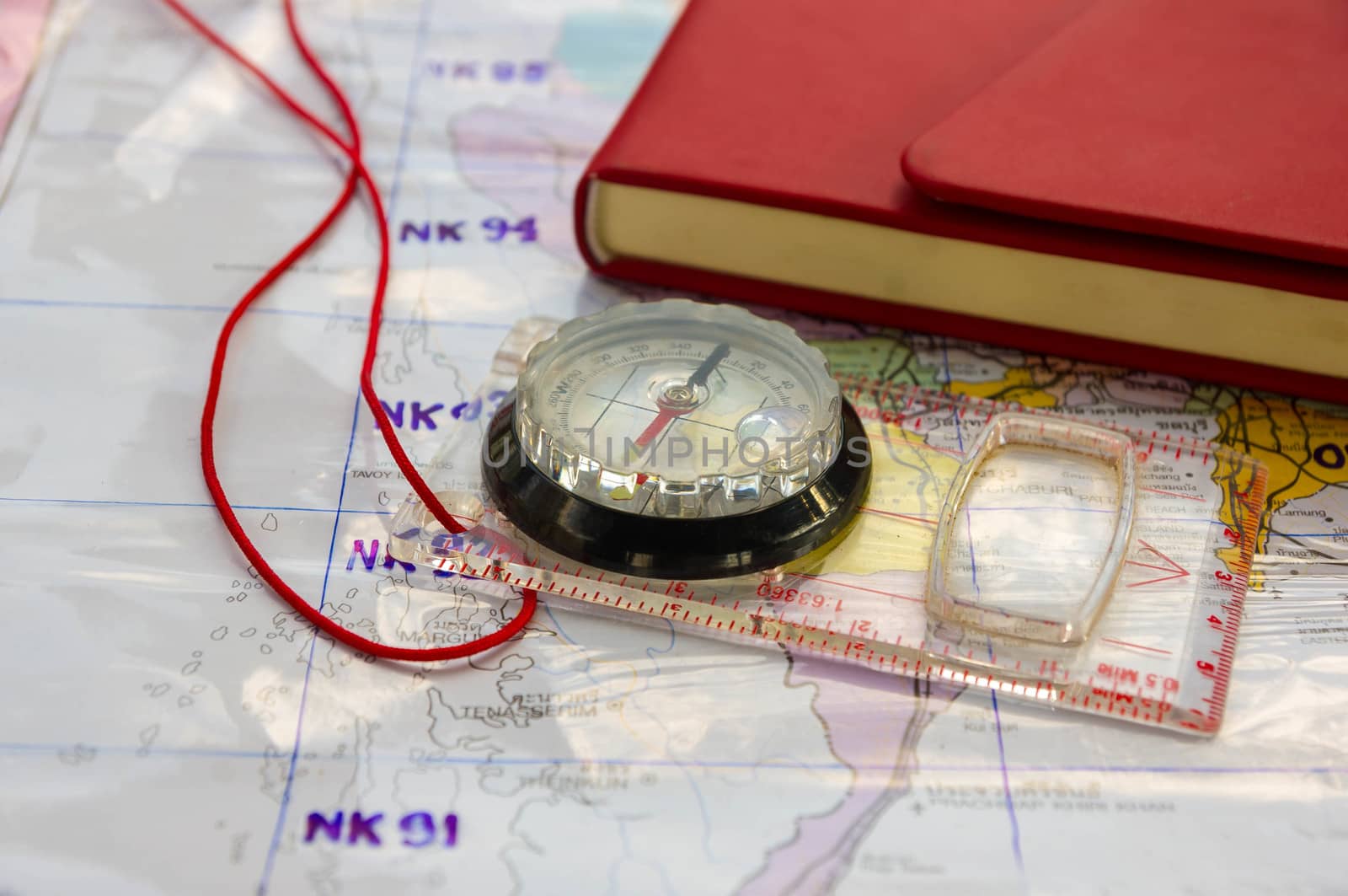 Compass and red Leather cover note book on Thailand map background.