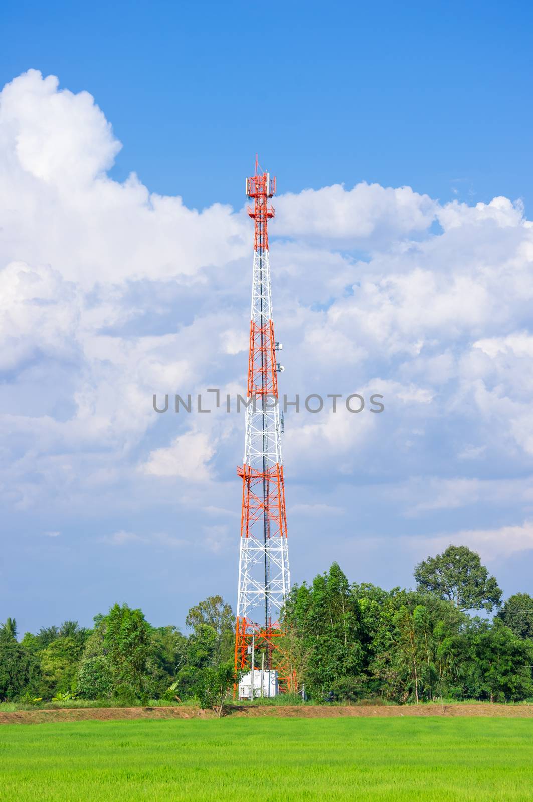 Telecommunication Radio Antenna and Satelite Tower with blue sky with cloud and green field.