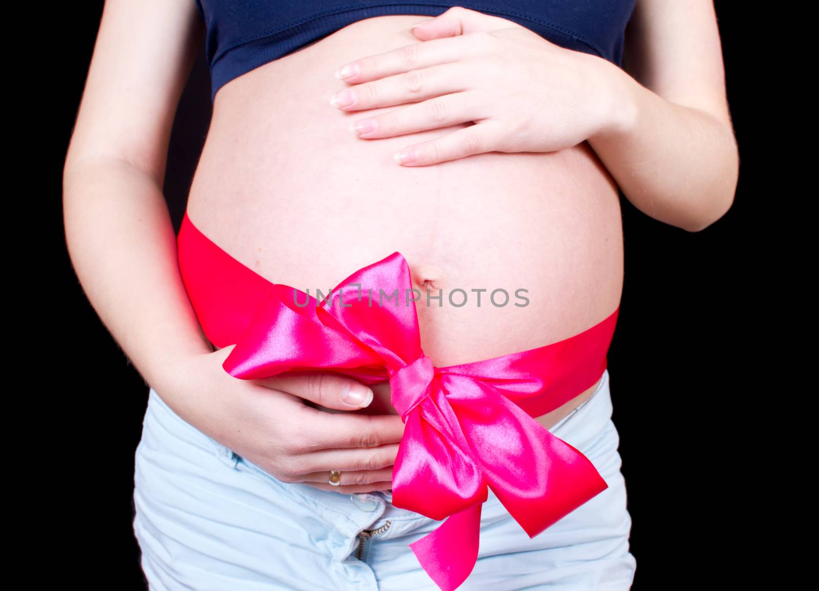 Pregnant belly tied with red satin ribbon