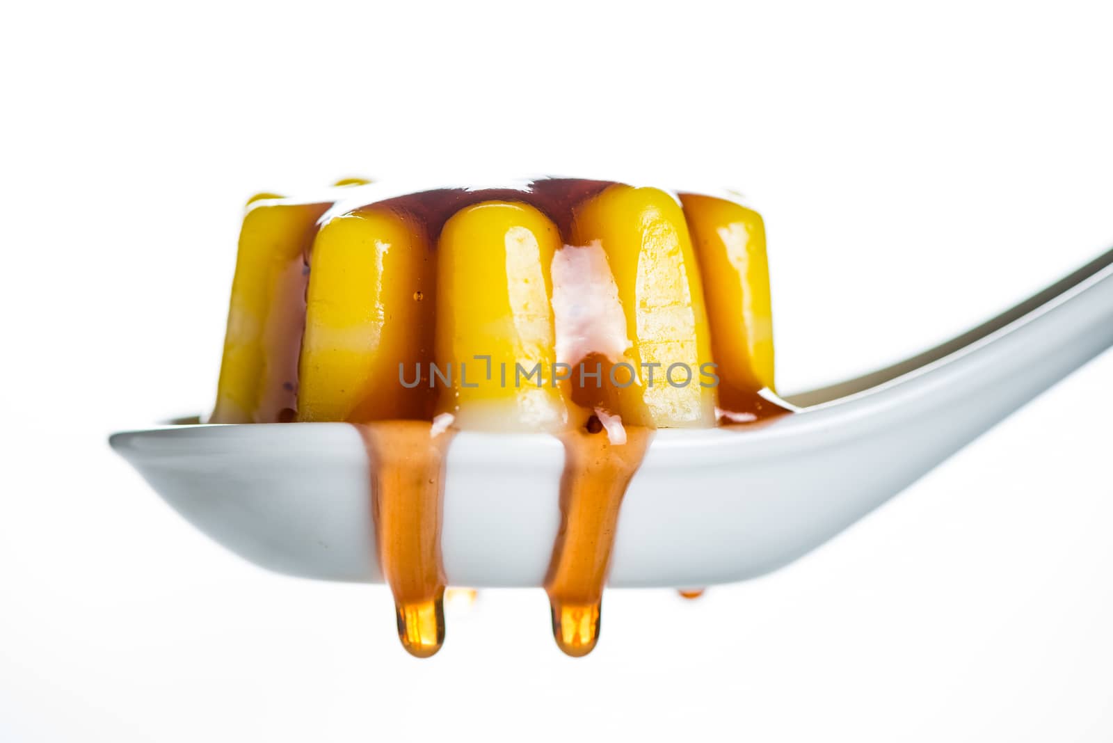 yellow jelly dessert made with coconuts  and fruit sauce on white spoon and white background