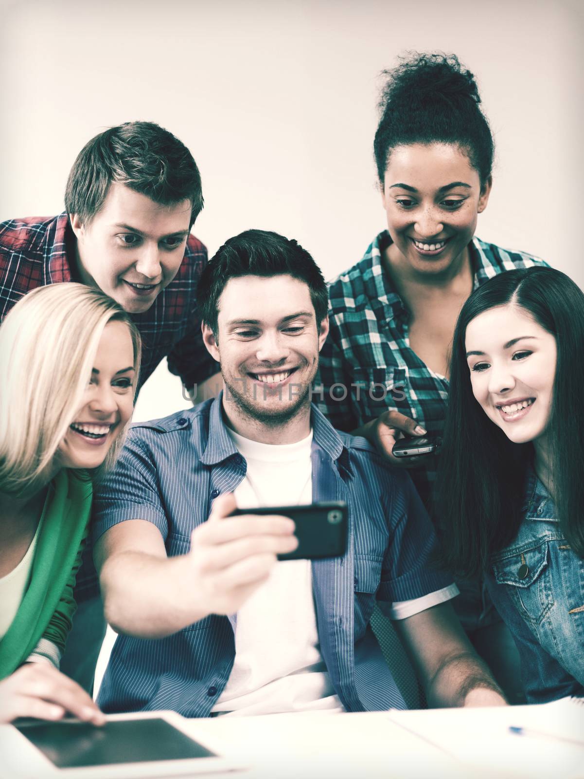 students looking into smartphone at school by dolgachov