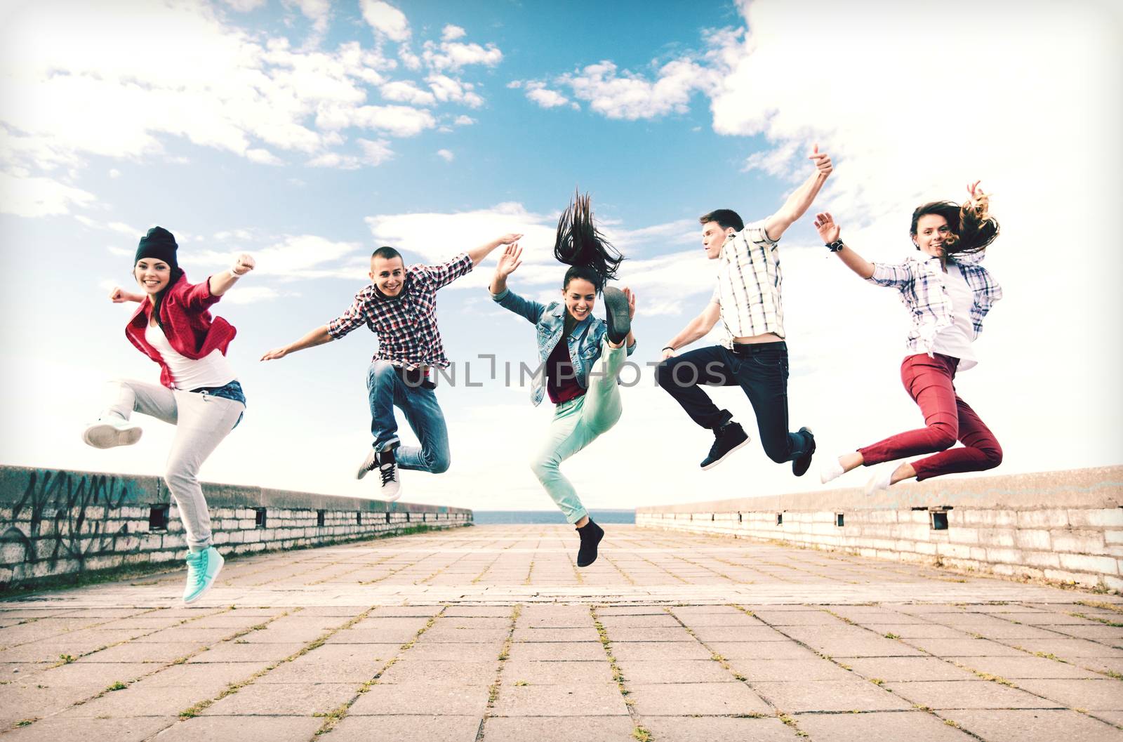 summer, sport, dancing and teenage lifestyle concept - group of teenagers jumping