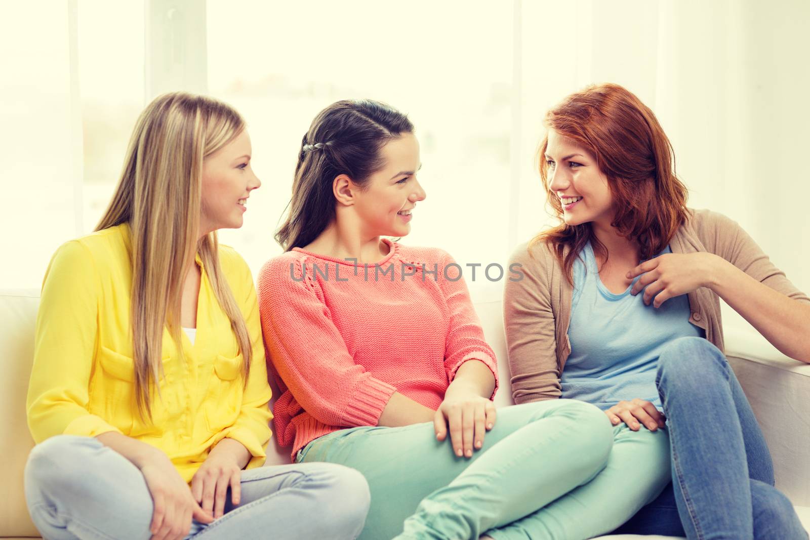 friendship and happiness concept - three girlfriends having a talk at home