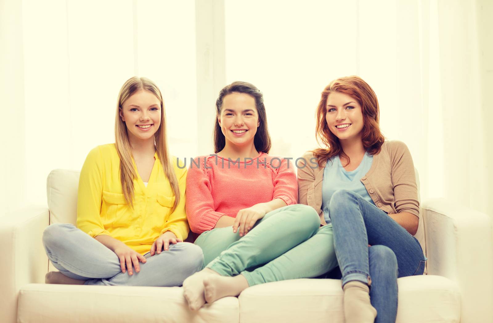 friendship and happiness concept - three girlfriends having a talk at home