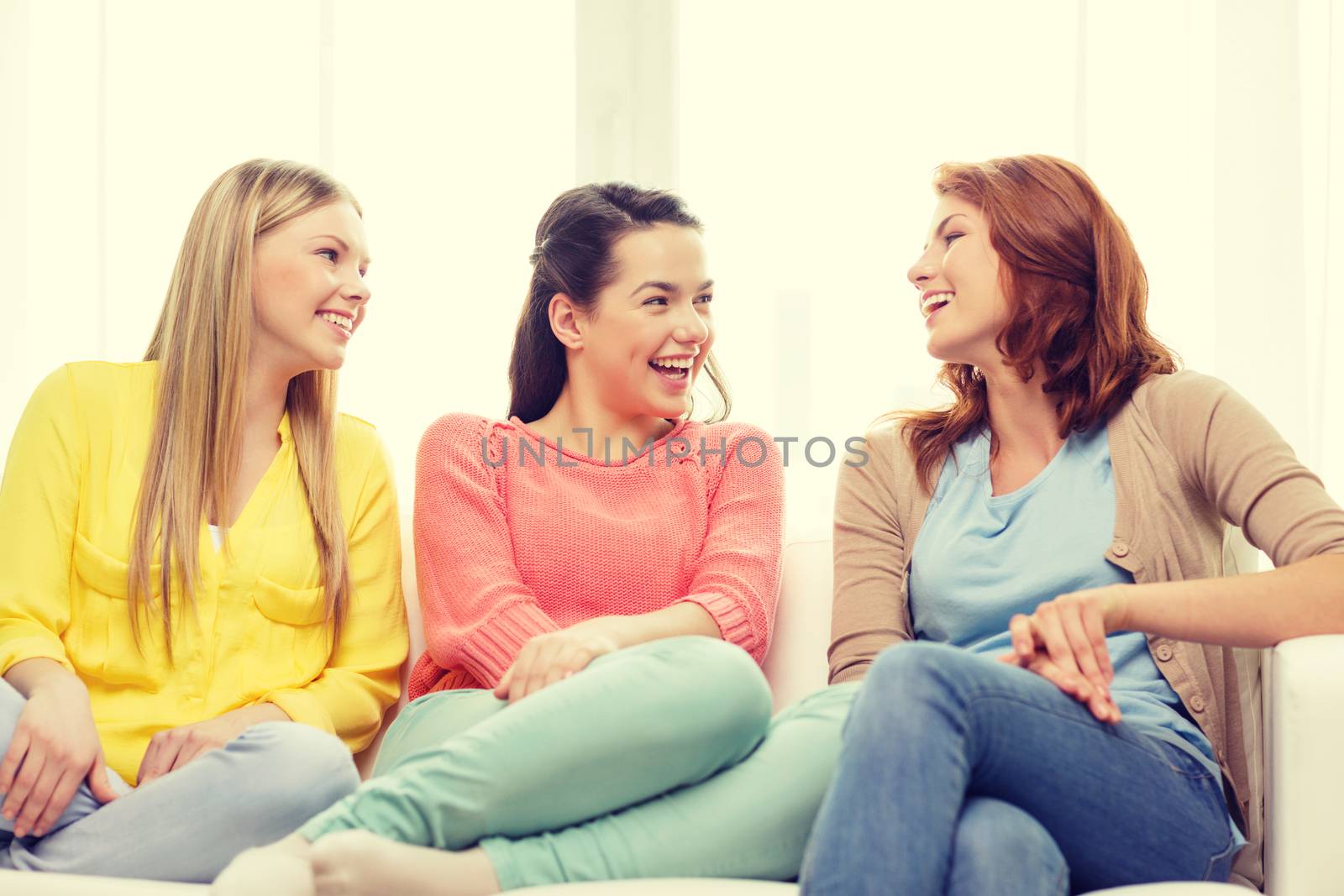 friendship and happiness concept - three girlfriends having a talk at home