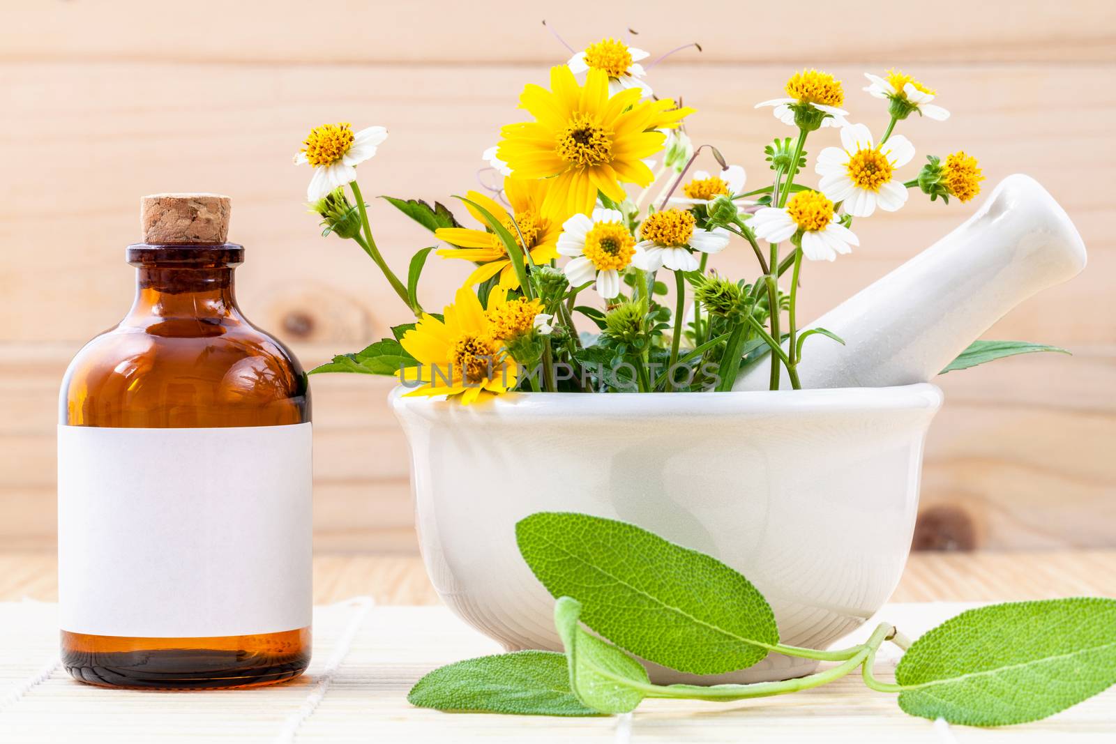 Alternative health care fresh herbal ,oil and wild flower with mortar on wooden background.