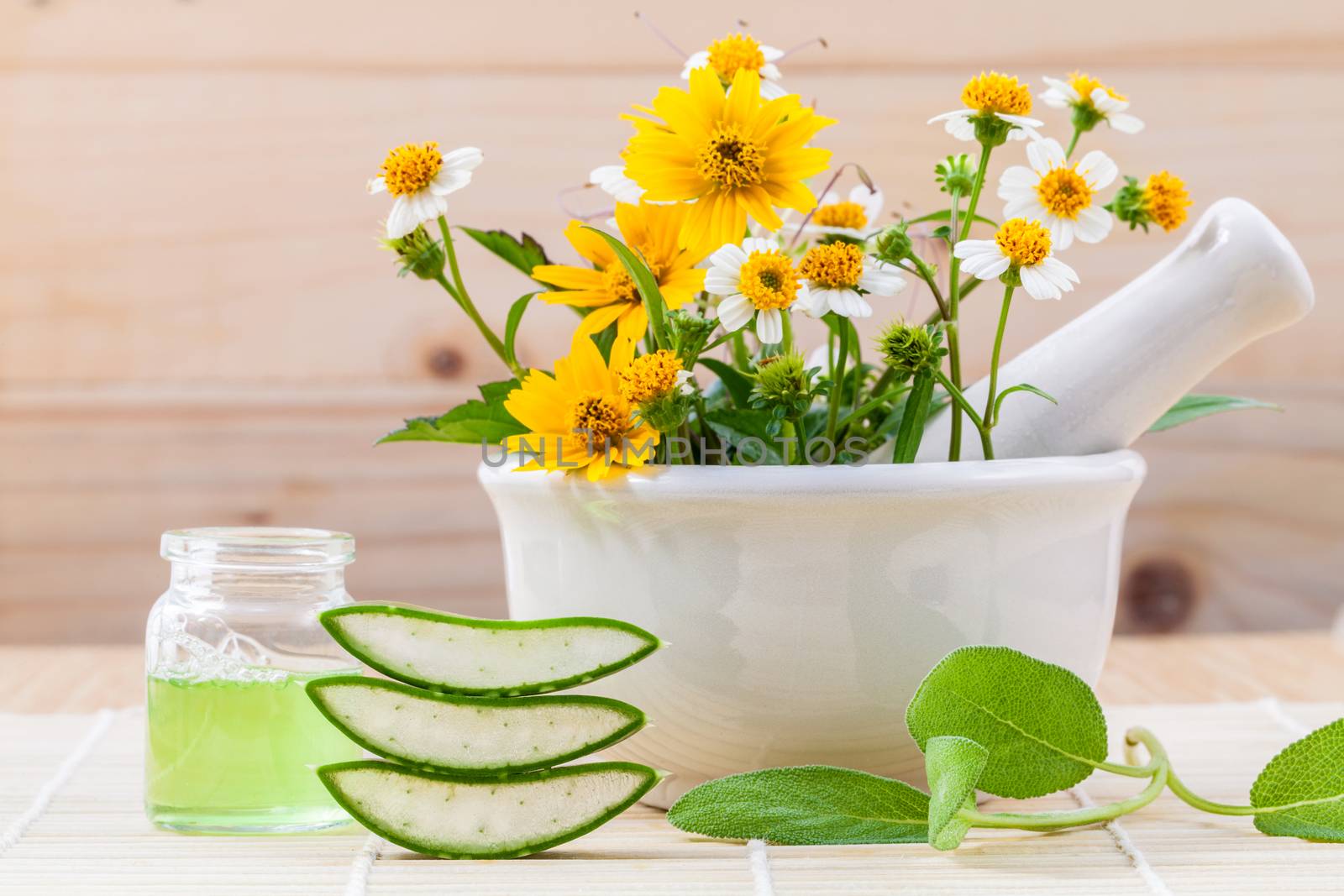 Alternative health care fresh herbal Aloe vera , oil and wild flower with mortar on wooden background.