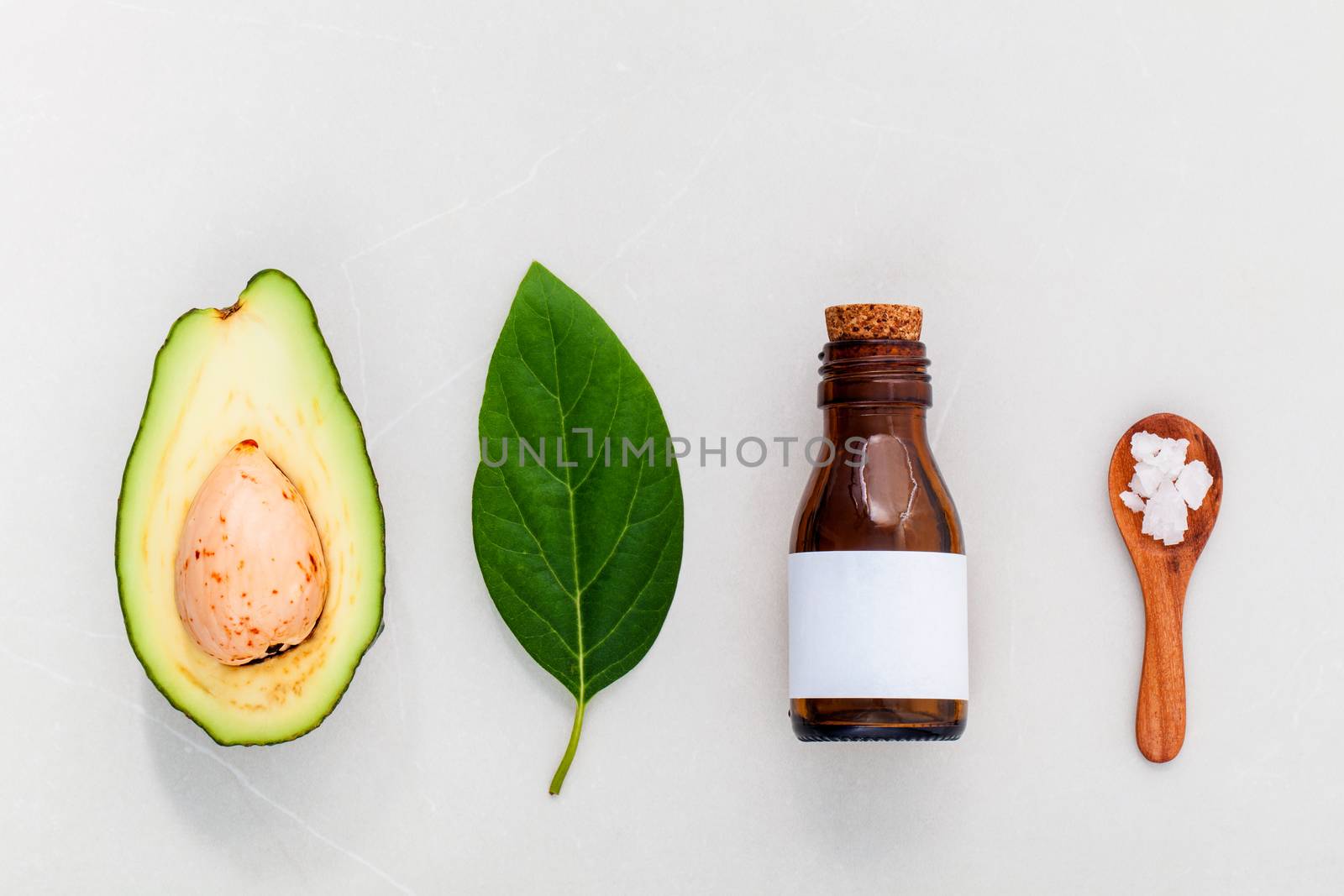 Alternative skin care  and scrub fresh  avocado , leaves ,sea salt and oils on marble background.