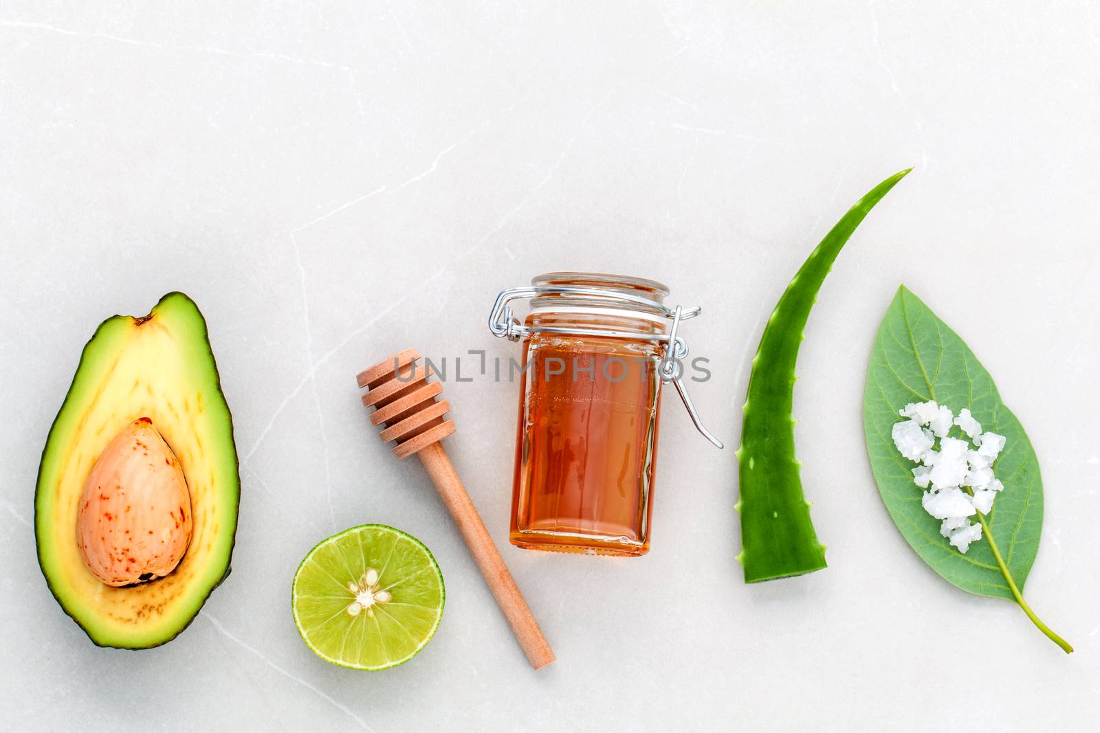 Alternative skin care  and scrub fresh  avocado , leaves ,sea salt , oils, lime and honey on marble background.