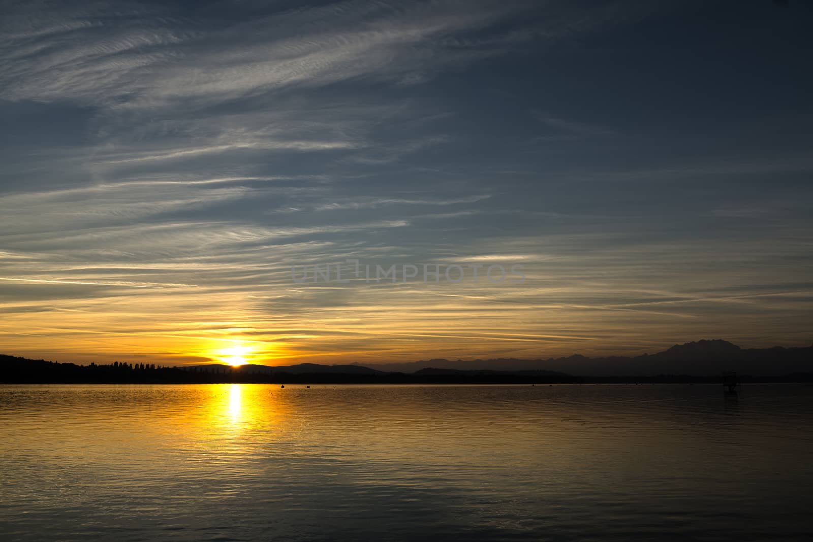 Sunset on the Varese lake in autumn season with blue sky and clouds in background