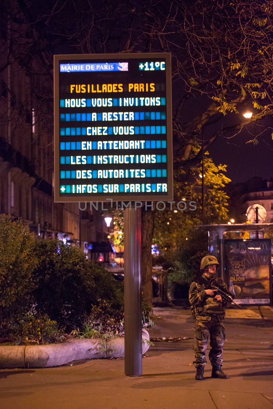 FRANCE, Paris: A French soldier stands under an information sign which reads 'We invite you to stay home and wait for forther instructions from the authorities', in the 11th arrondissement of Paris, close to Nation square and boulevard Voltaire, on November 14, 2015, few hours after terror attacks in the French capital.