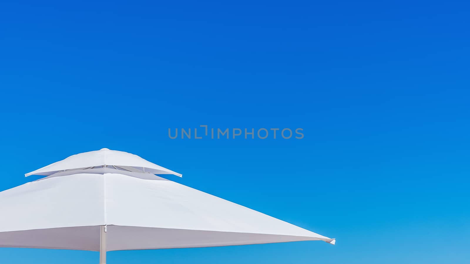 White beach umbrella at the clean blue sky.