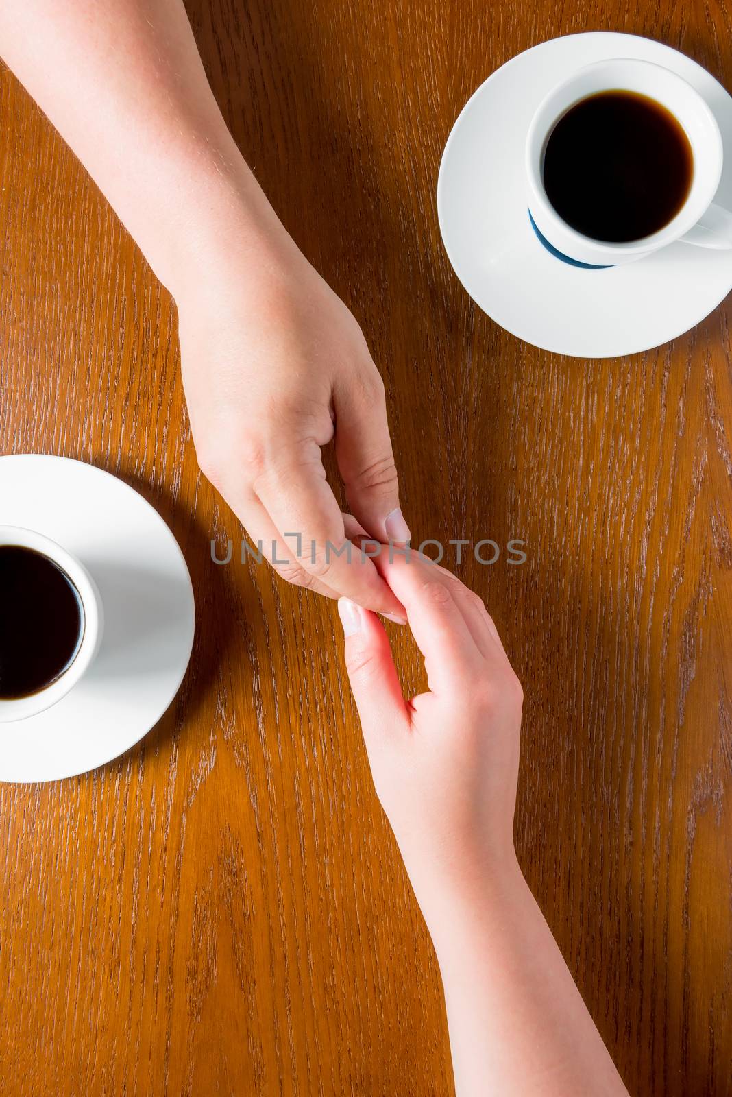 couple holding hands on the table in the cafe and coffee cup