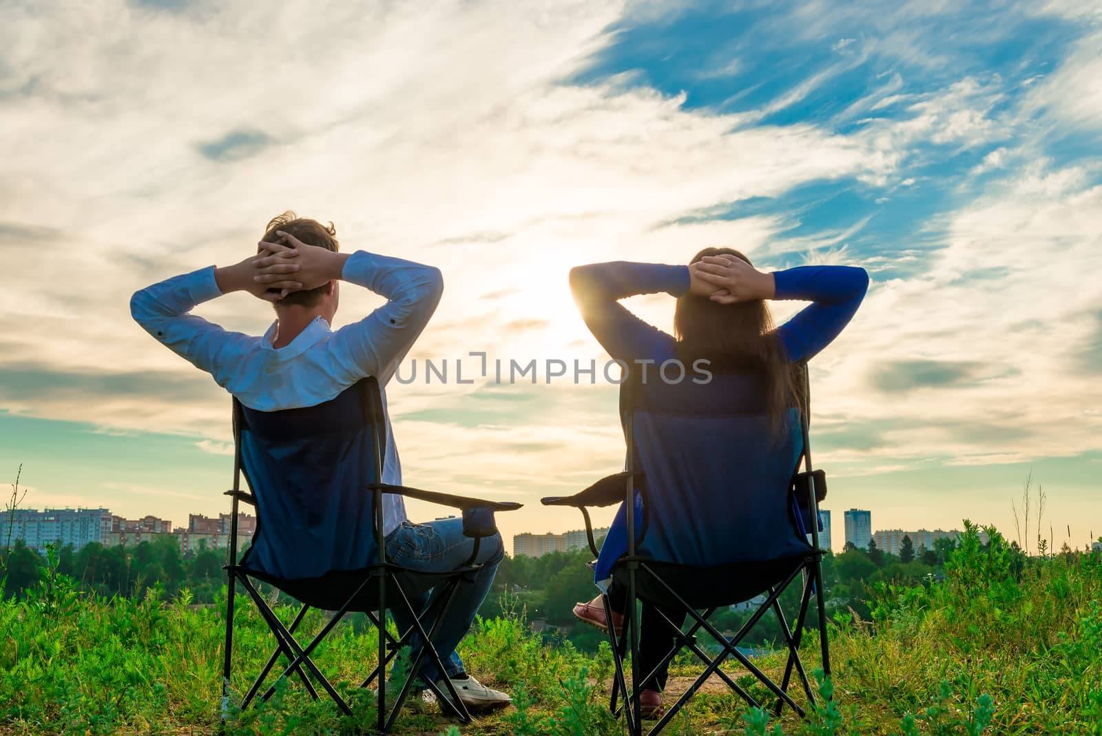 couple sitting in chairs and admire the sunrise over the city