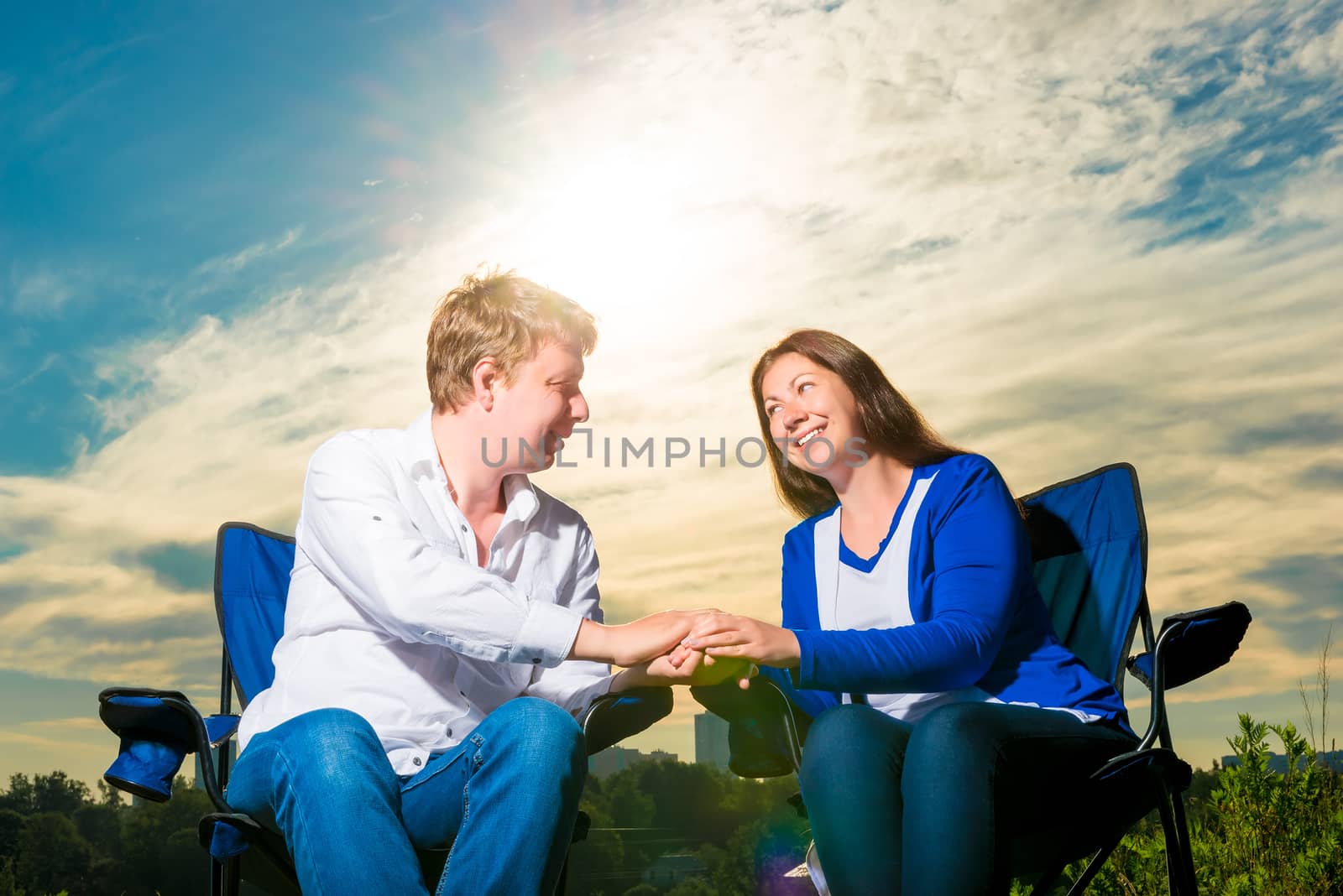 portrait of happy loving couple at sunrise on chairs outdoors