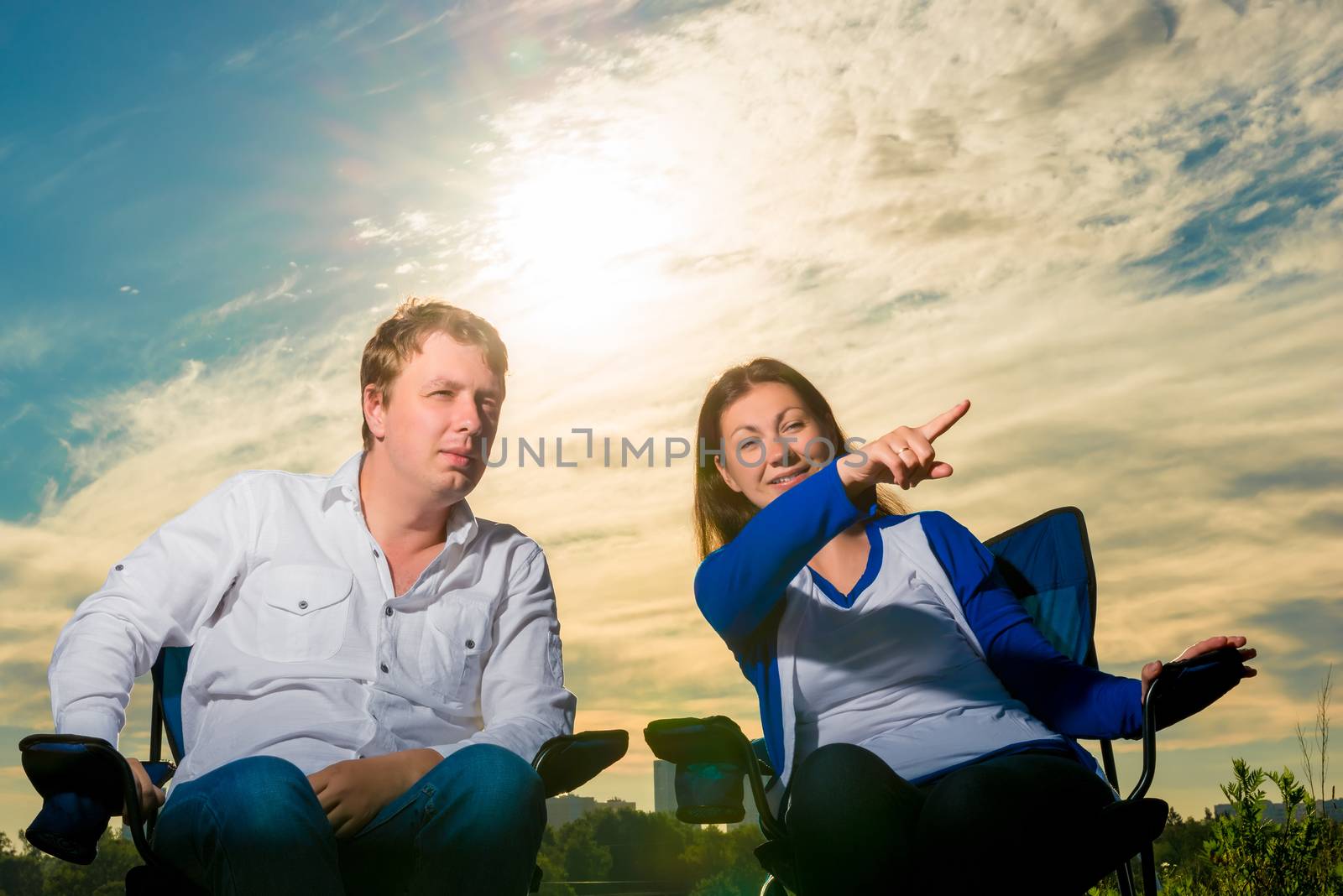 couple relaxes in the chairs and look in the direction