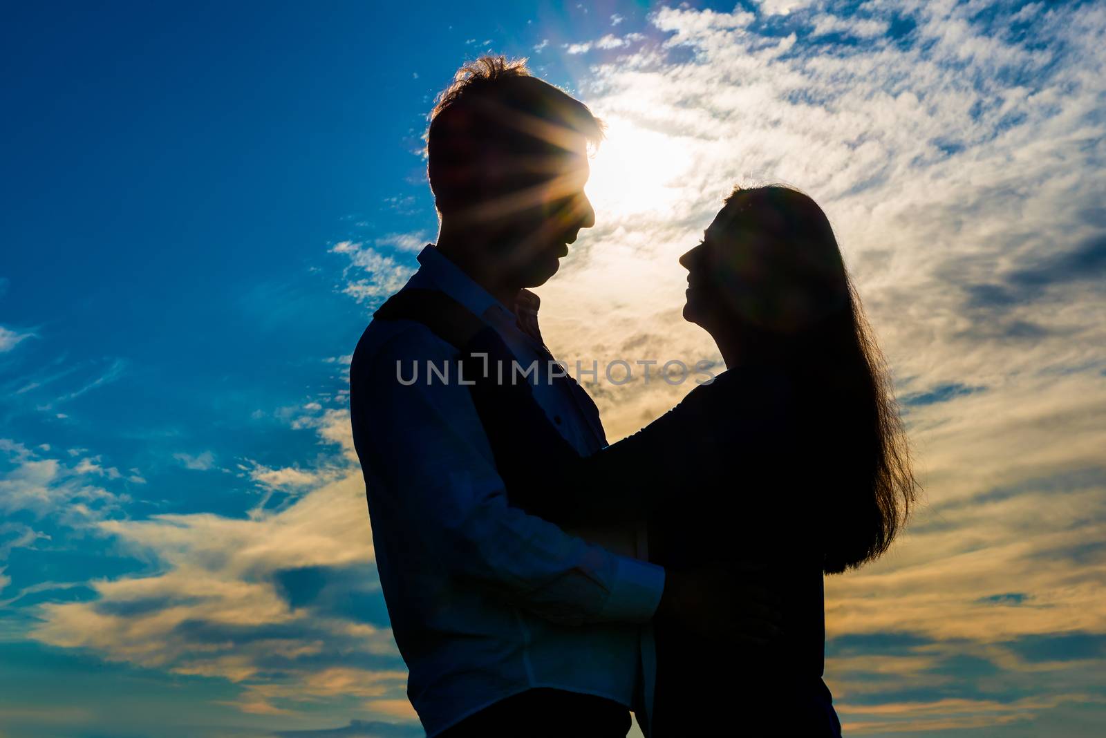 silhouette of a loving couple hugging at sunset by kosmsos111