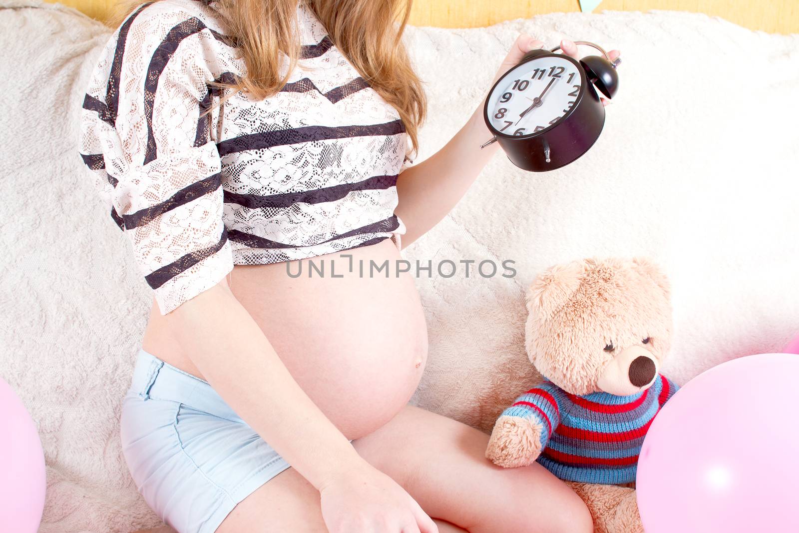 Pregnant woman sitting on the couch with alarm